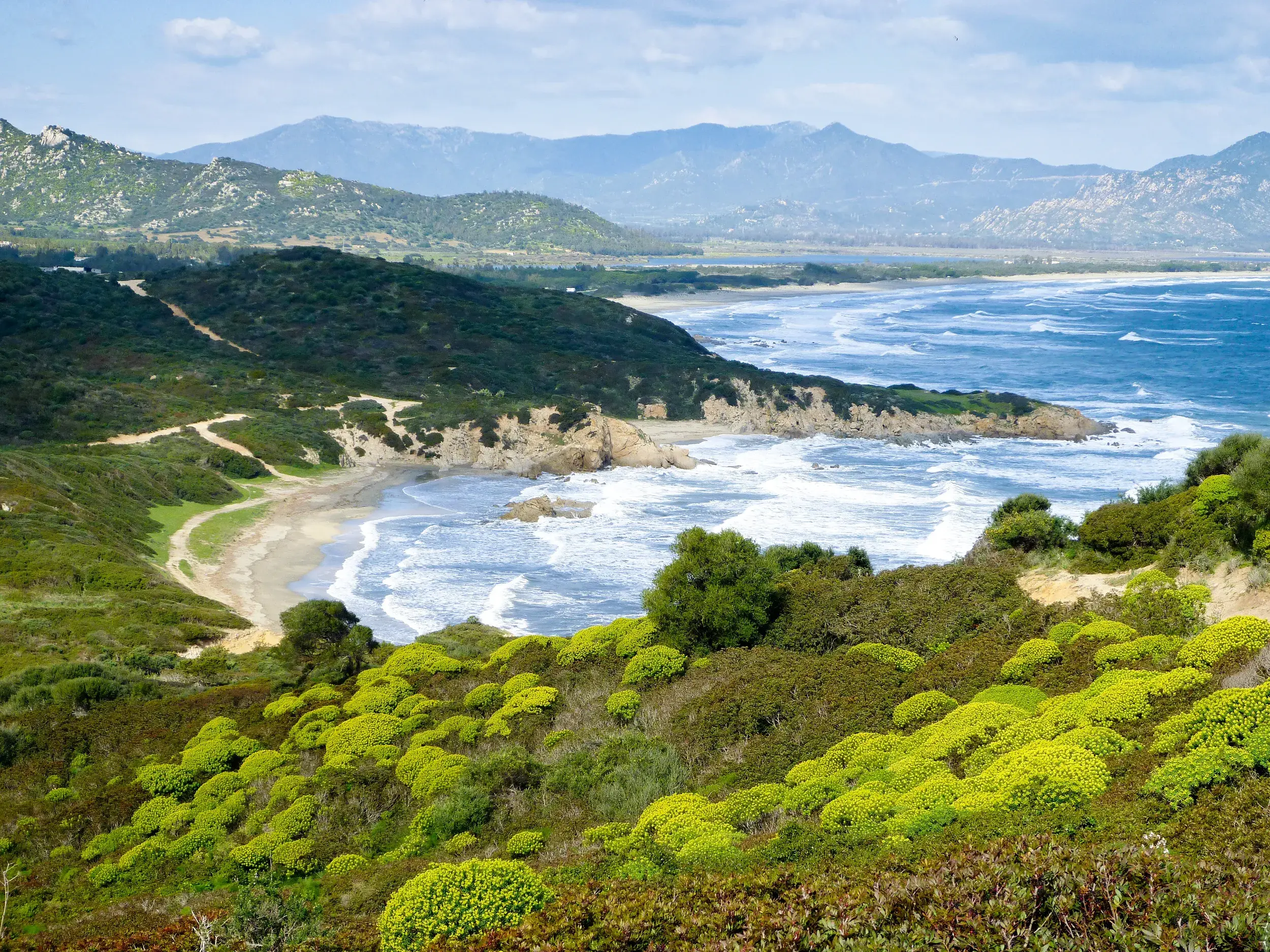 Ausblick bei einer Küstenwanderung am Capo Pecora auf Sardiniens wilde Küste mit grüner Macchia und einer malerischen Bucht.