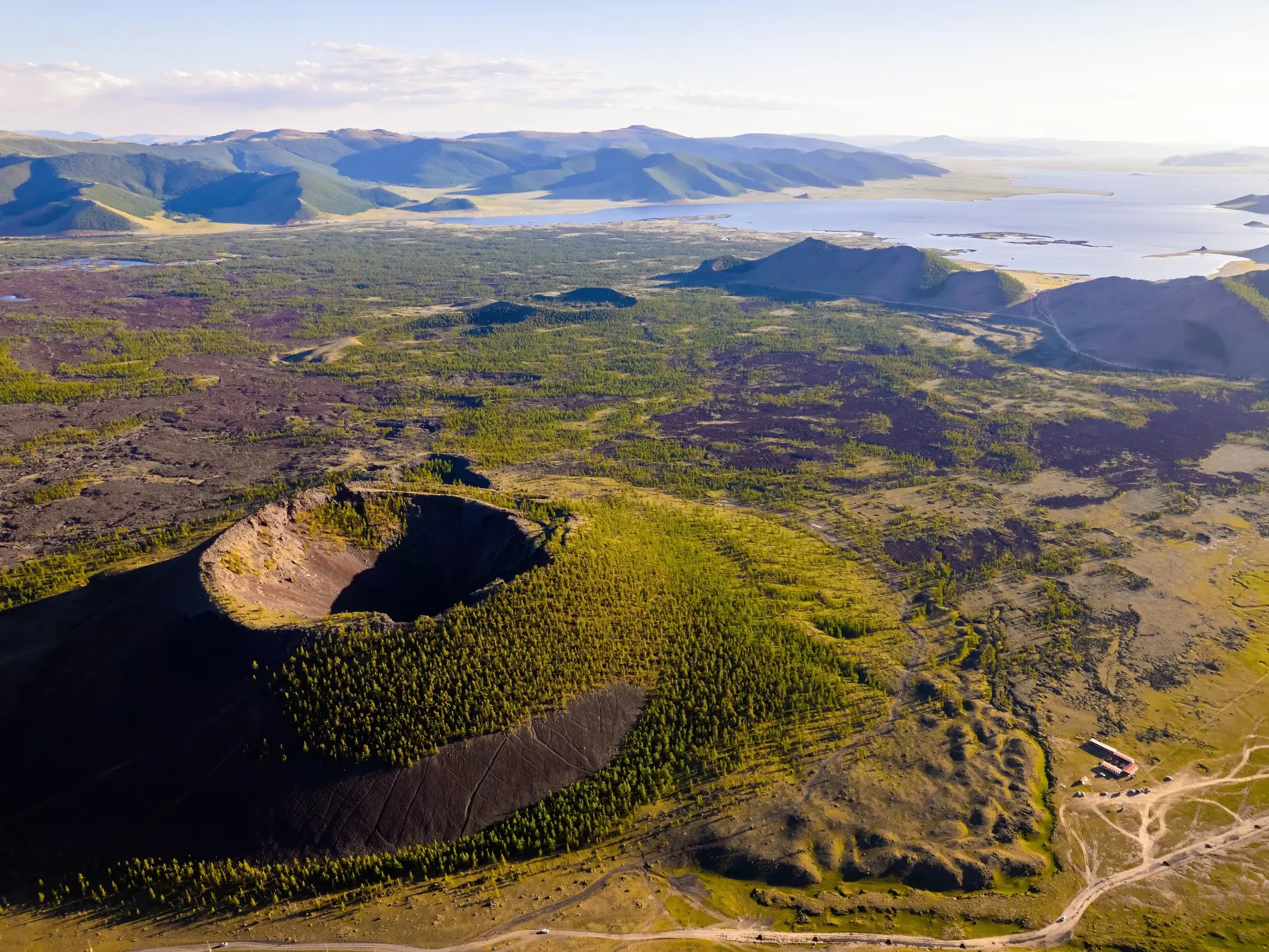 Der bewaldete Vulkankrater Khorgo aus der Vogelperspektive mit Blick auf den weiten Terkhiin Tsagaan-See in der Mongolei.
