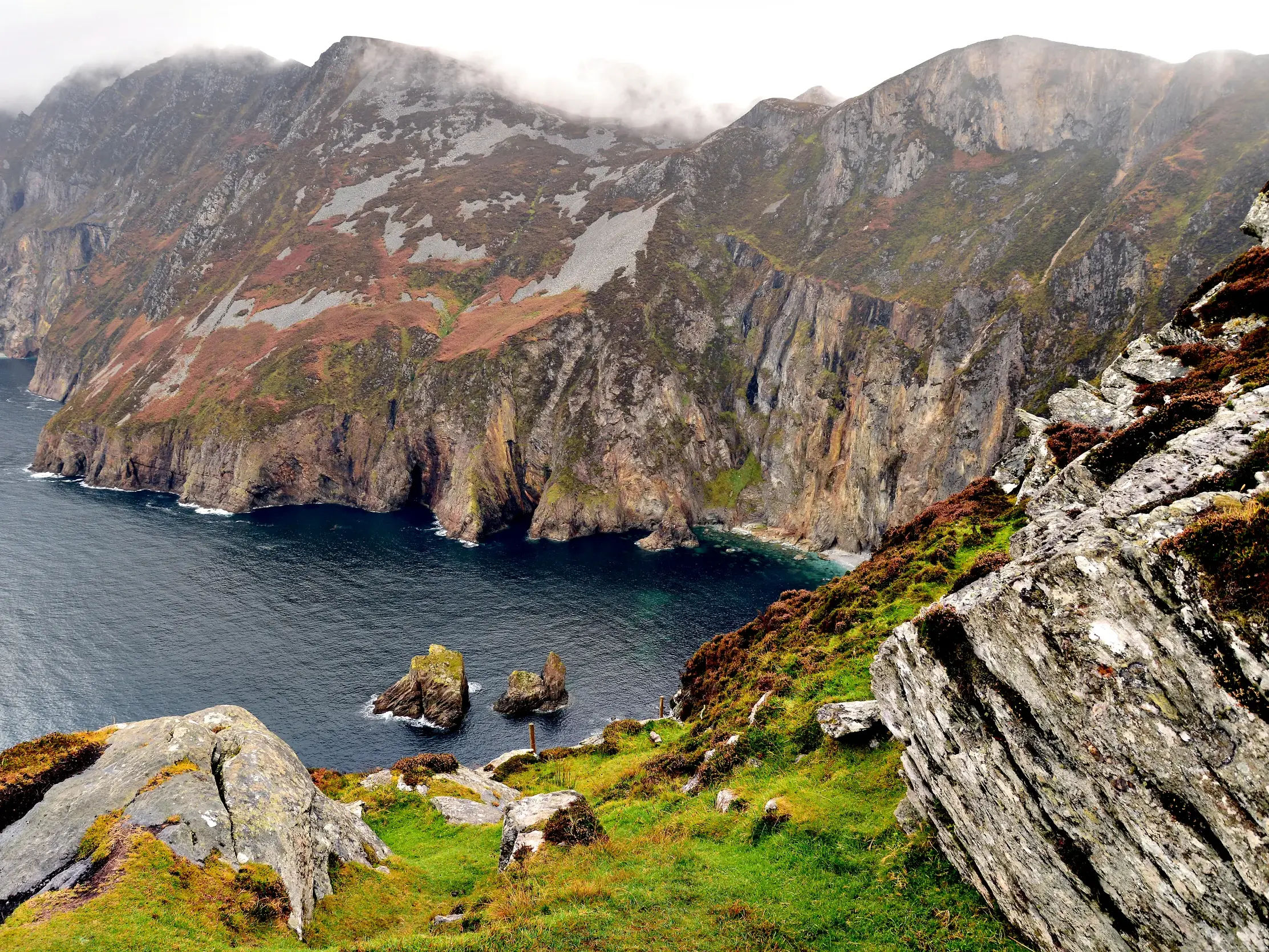 Majestätischer Ausblick beim Wandern auf die nebelverhangenen Klippen von Slieve League und den rauen Atlantik in Irland.