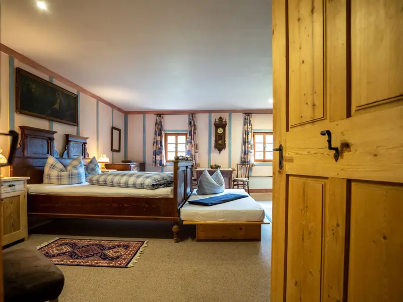 Rustikales Schlafzimmer im denkmalgeschützten Wurzerhof im Villgratental mit Holzbett und traditioneller Einrichtung.
