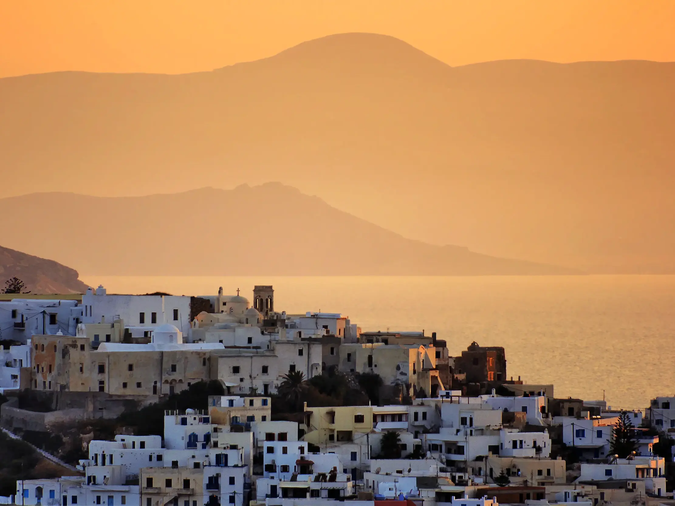 Die typischen weißen Häuser von Naxos-Stadt an der Küste der Ägäis, in das goldene Licht des Sonnenuntergangs getaucht.