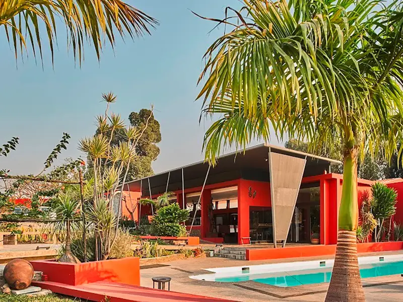 Casper Lodge in Lubango mit einladendem Pool, umgeben von tropischen Palmen bei sonnigem Wetter in Angola.