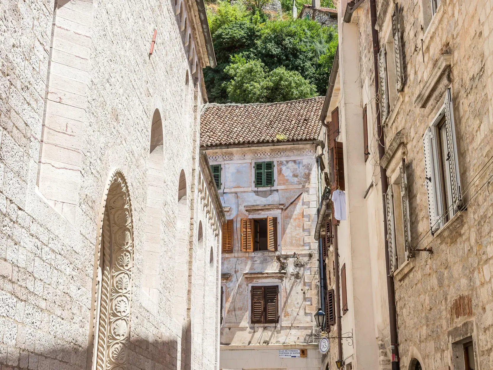 Eine schmale Gasse mit historischen Steinfassaden und Fensterläden in der Altstadt von Kotor, einem UNESCO-Welterbe in Montenegro.
