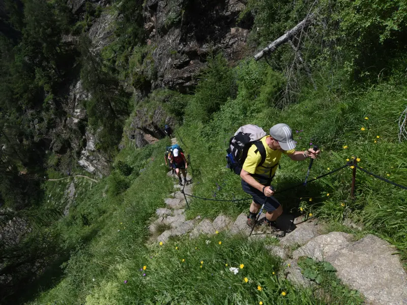 Eine Hauser Wandergruppe überwindet gesichert die steilen Steinstufen der 1000-Stufenschlucht am Meraner Höhenweg in Südtirol.