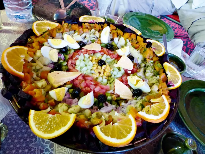 Farbenfroher marokkanischer Salat mit Eiern, Oliven, Käse und Gemüse, zubereitet vom Trekkingkoch während der Tour im Hohen Atlas.