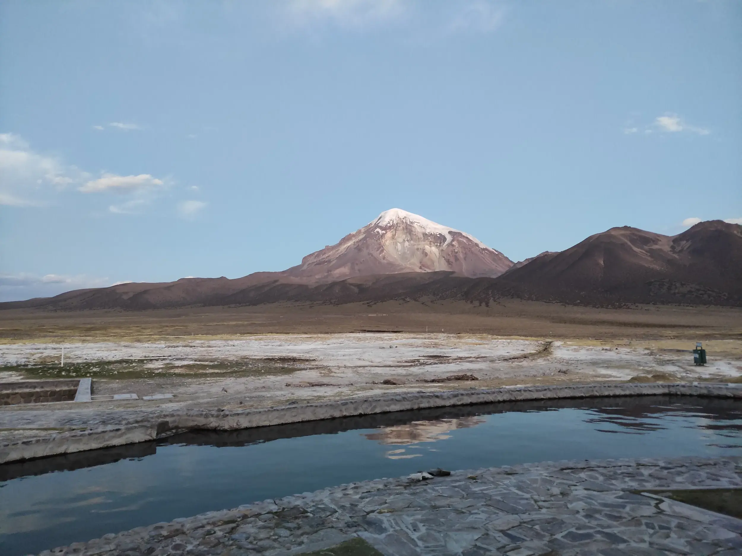 Steinernes Thermalbecken in den heißen Quellen des Sajama Nationalparks mit Panoramablick auf den schneebedeckten Vulkan Sajama.