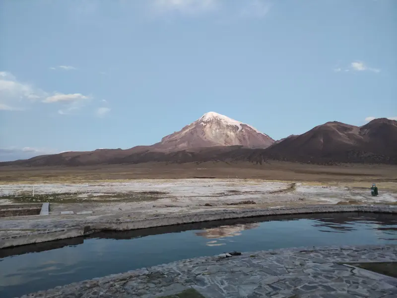 Steinernes Thermalbecken in den heißen Quellen des Sajama Nationalparks mit Panoramablick auf den schneebedeckten Vulkan Sajama.