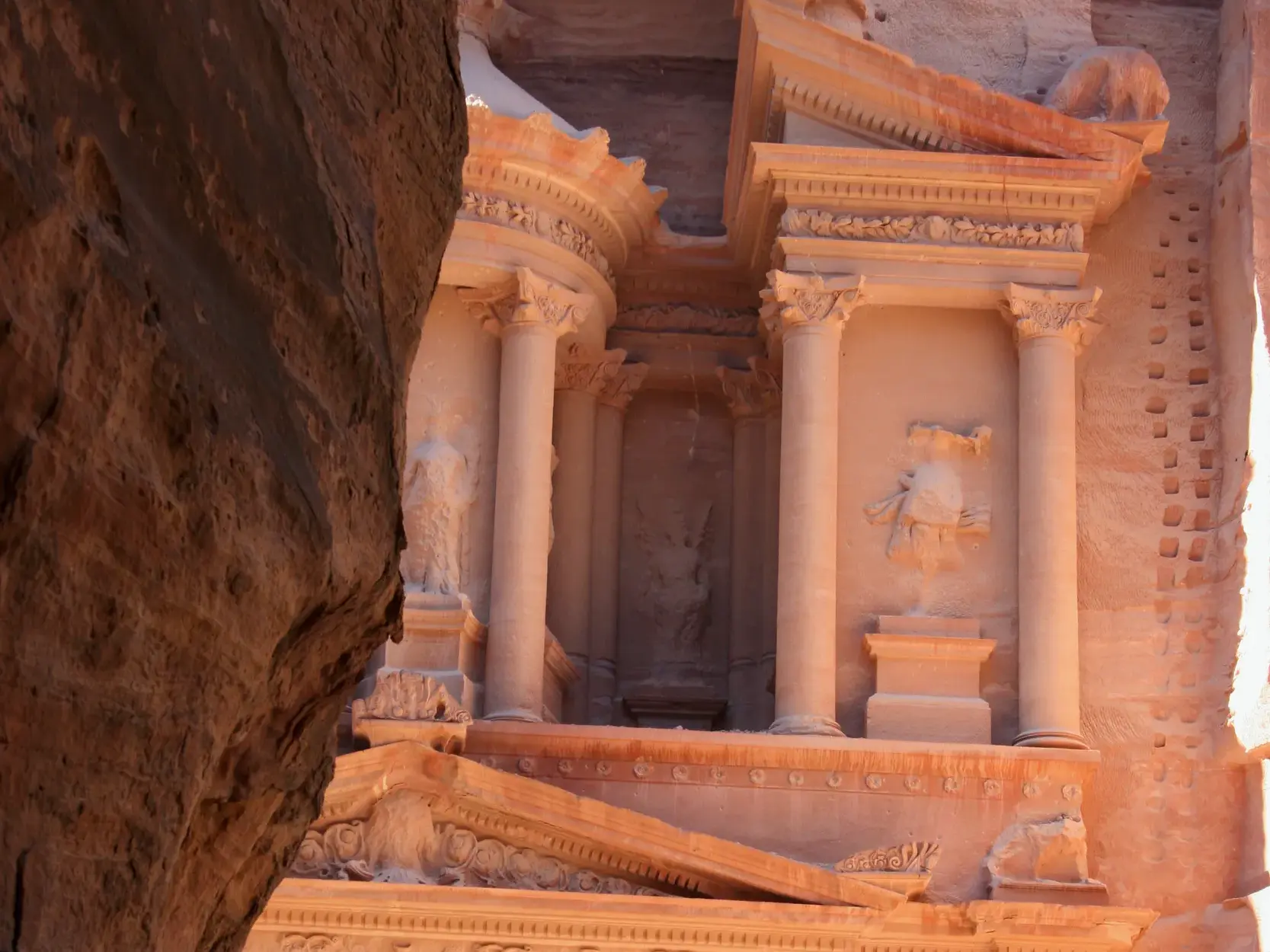 Blick aus der Felsenschlucht Siq auf die sonnenbeschienene Fassade des Schatzhauses Al-Khazneh in Petra, Jordanien.