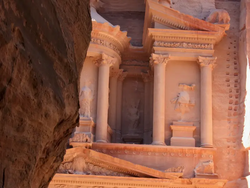 Blick aus der Felsenschlucht Siq auf die sonnenbeschienene Fassade des Schatzhauses Al-Khazneh in Petra, Jordanien.