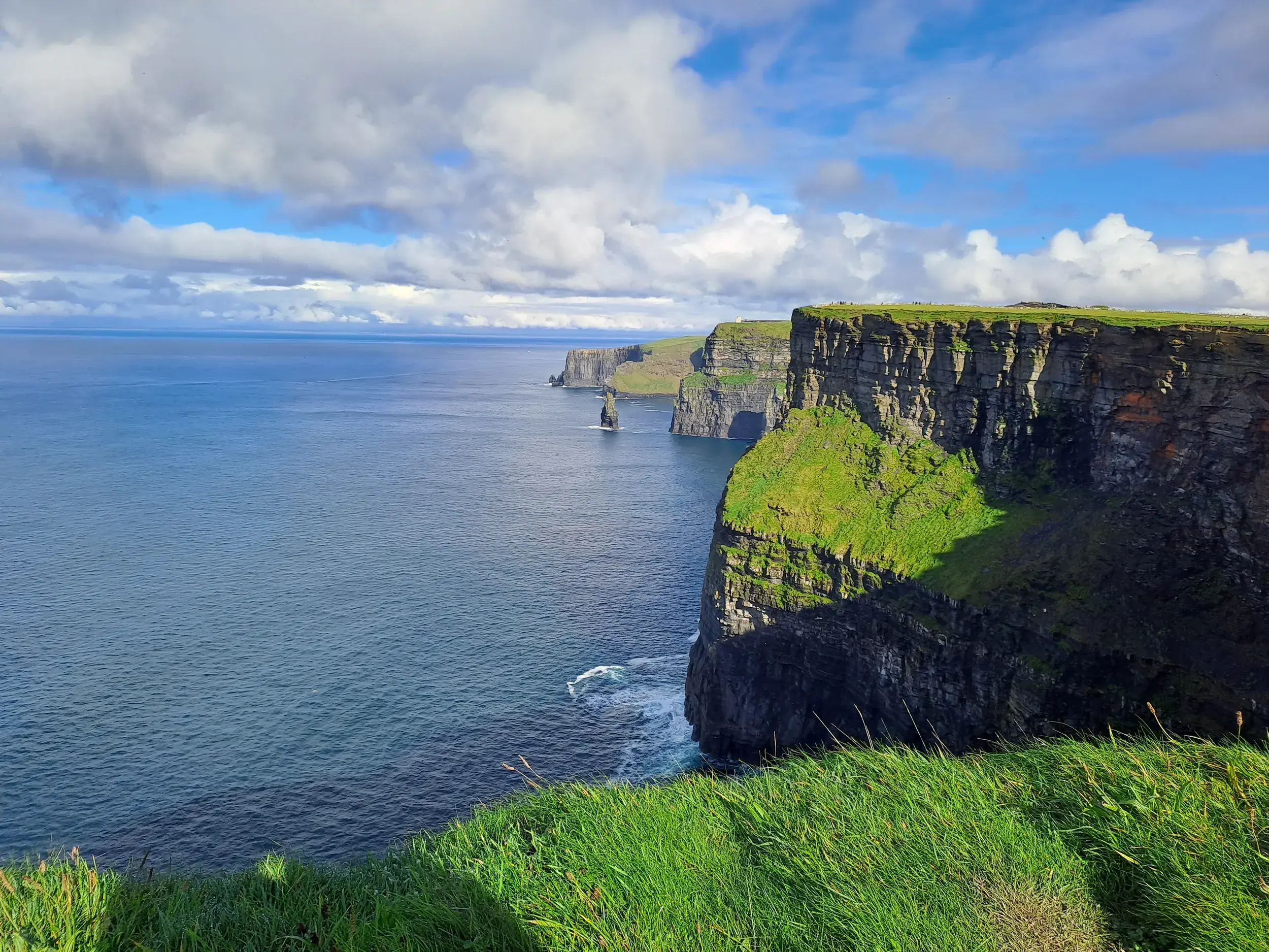 Die Steilklippen der Cliffs of Moher an der Westküste von Irland ragen bei Sonnenschein aus dem blauen Atlantik.
