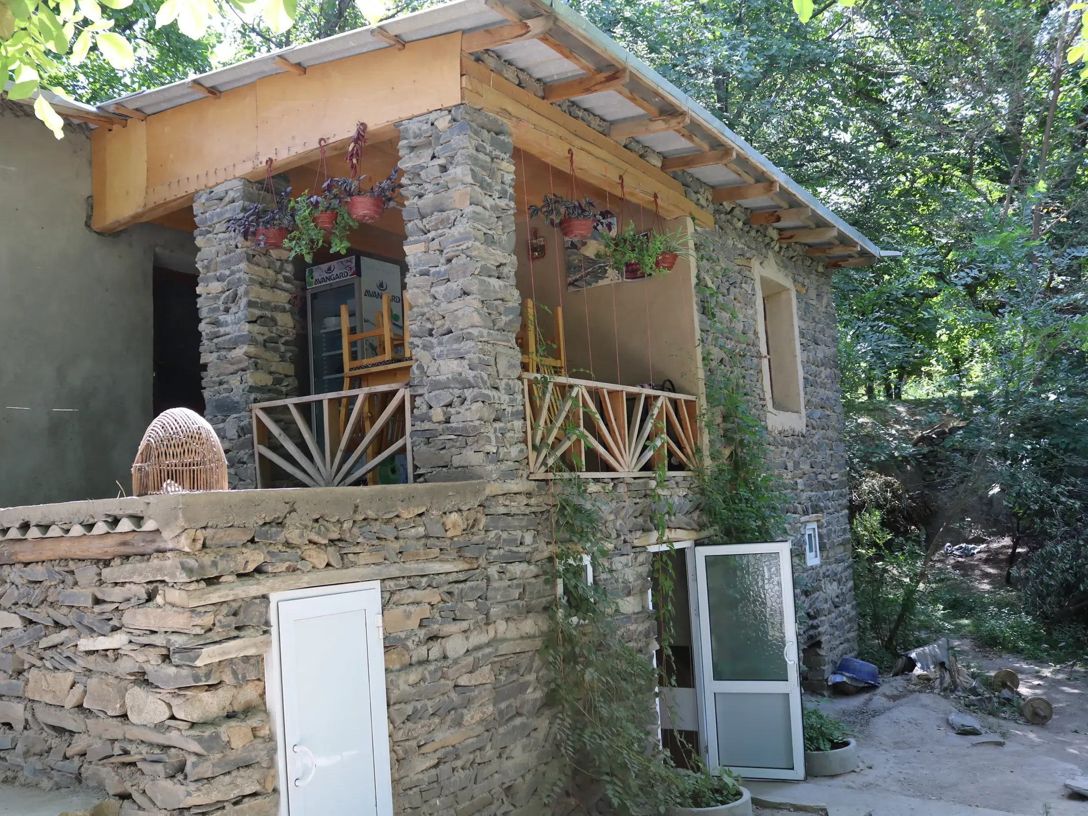 Ein Homestay des gemeindebasierten Tourismus-Projekts im Nuratau-Gebirge mit Steinmauern und einem Holzbalkon.