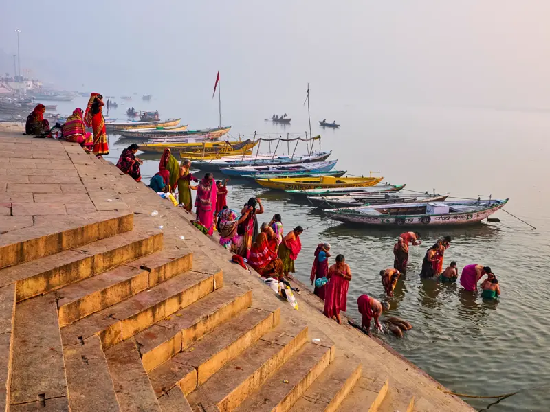 Indische Frauen in bunten Saris bei der rituellen Waschung an den Ghats des heiligen Ganges in Varanasi am Morgen.
