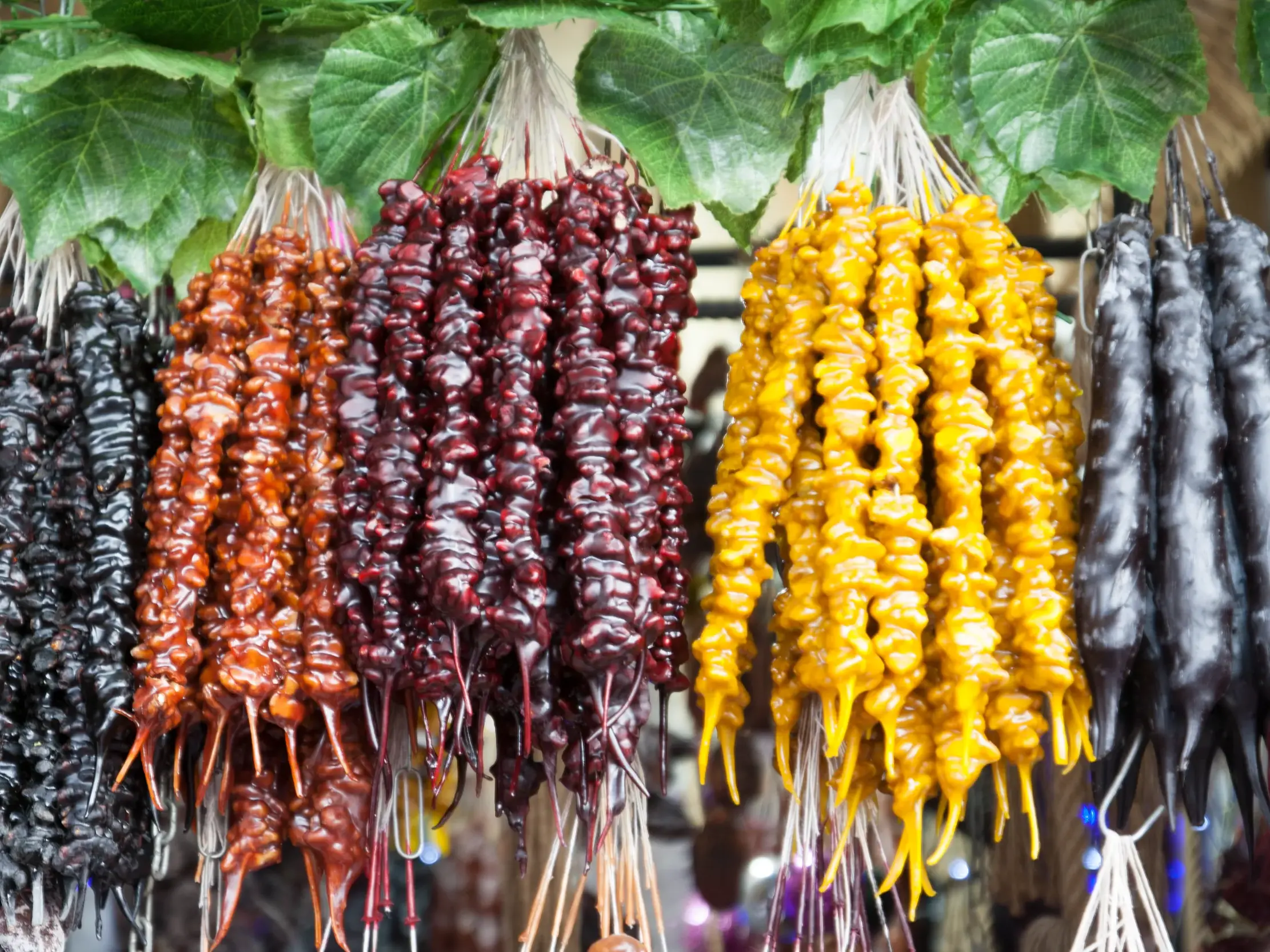 Farbenfrohe Churchkhela, eine georgische Spezialität, hängen in Bündeln auf einem Bauernmarkt in der Weinregion Kachetien.