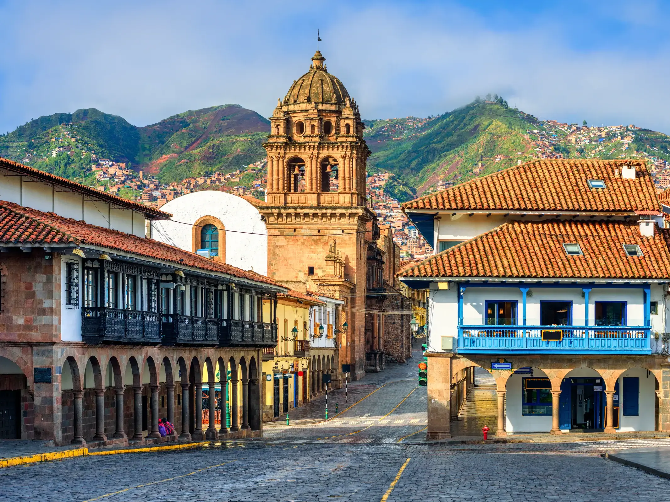 Kolonialbauten und ein Kirchturm in Cusco, der ehemaligen Hauptstadt der Inkas, vor der beeindruckenden Kulisse der Anden.
