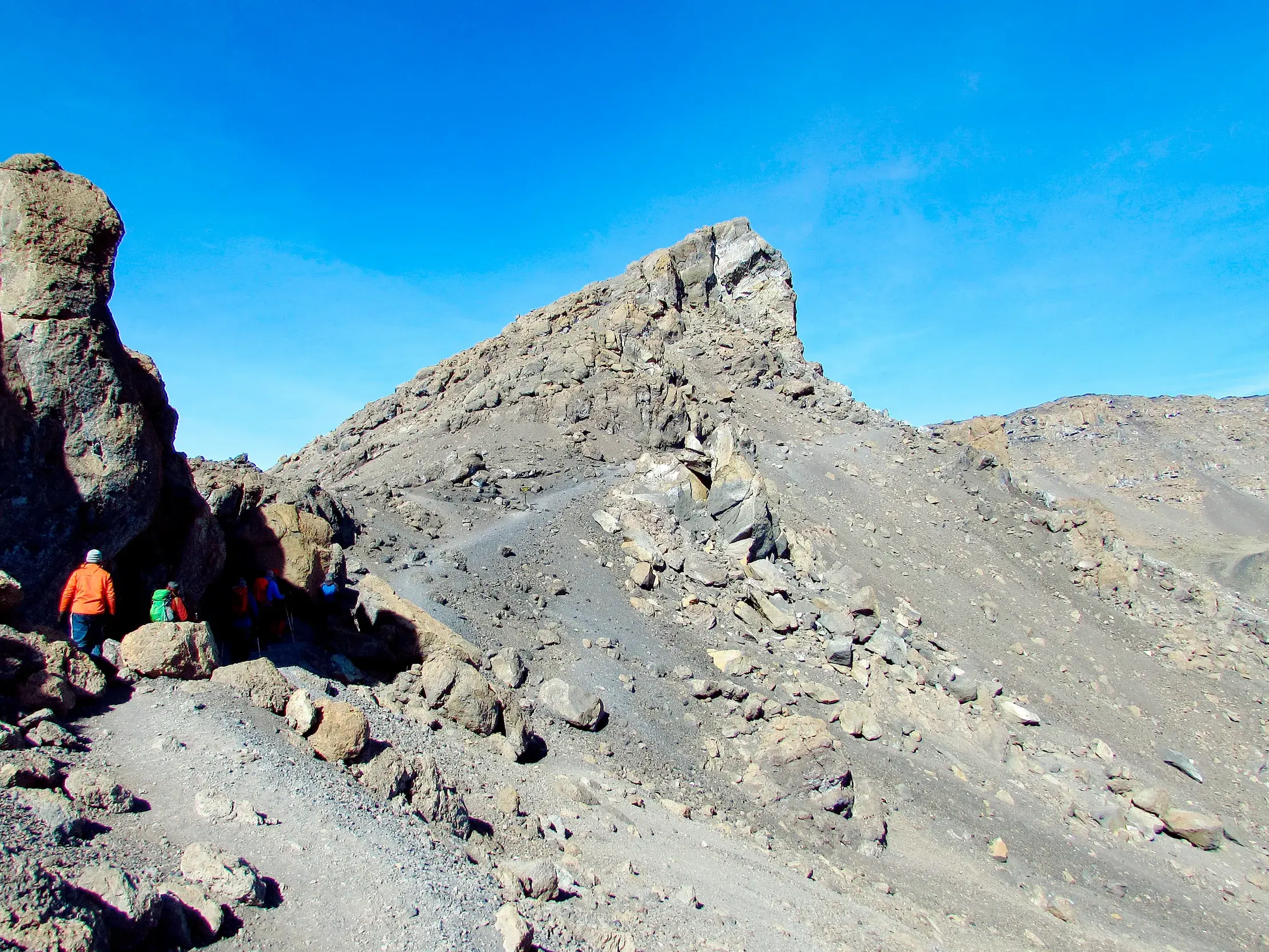 Hauser-Trekkinggruppe auf einem schmalen Pfad in der kargen, alpinen Wüstenzone des Kilimanjaro in Tansania.