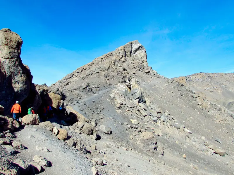 Hauser-Trekkinggruppe auf einem schmalen Pfad in der kargen, alpinen Wüstenzone des Kilimanjaro in Tansania.