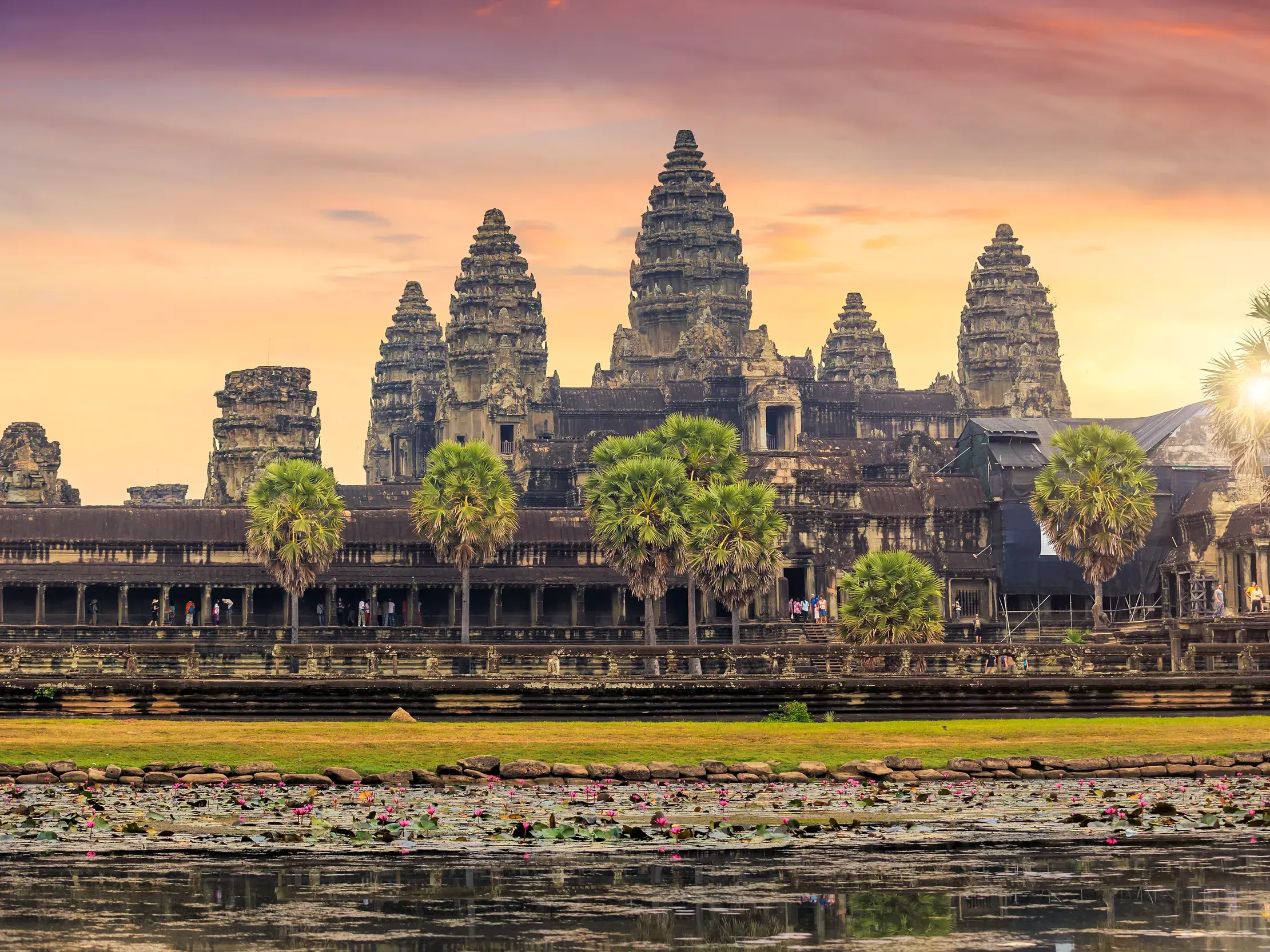 Majestätische Tempelanlage Angkor Wat in Siem Reap im warmen Licht des Sonnenuntergangs, gespiegelt im Seerosenteich.