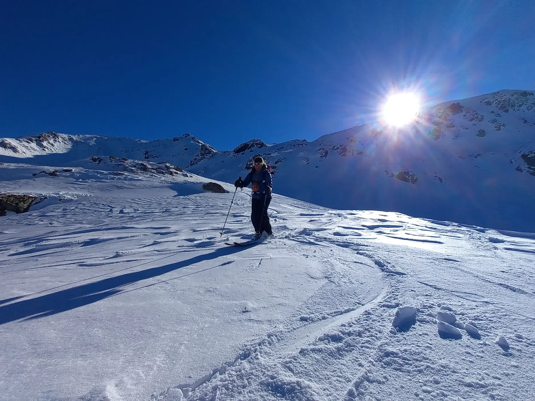 Eine Skitourengeherin genießt bei strahlendem Sonnenschein die weite Schneelandschaft im Sharr-Gebirge im Kosovo.