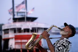 Ein Jazz-Saxofonist spielt mit Leidenschaft vor einem historischen Schaufelraddampfer auf dem Mississippi in New Orleans.