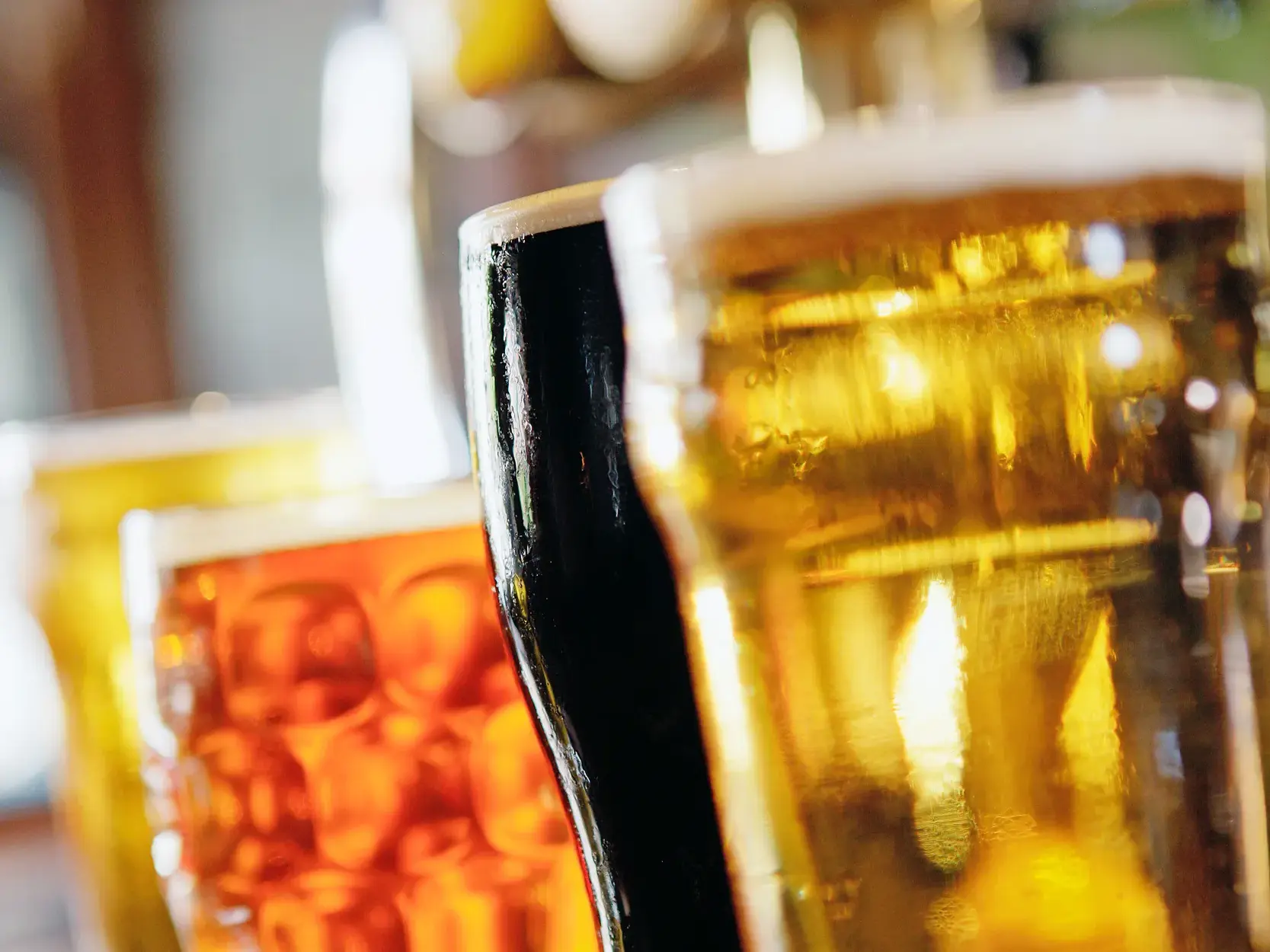 Verschiedene britische Biersorten in Gläsern auf dem Tresen eines gemütlichen Gastro-Pubs in London.