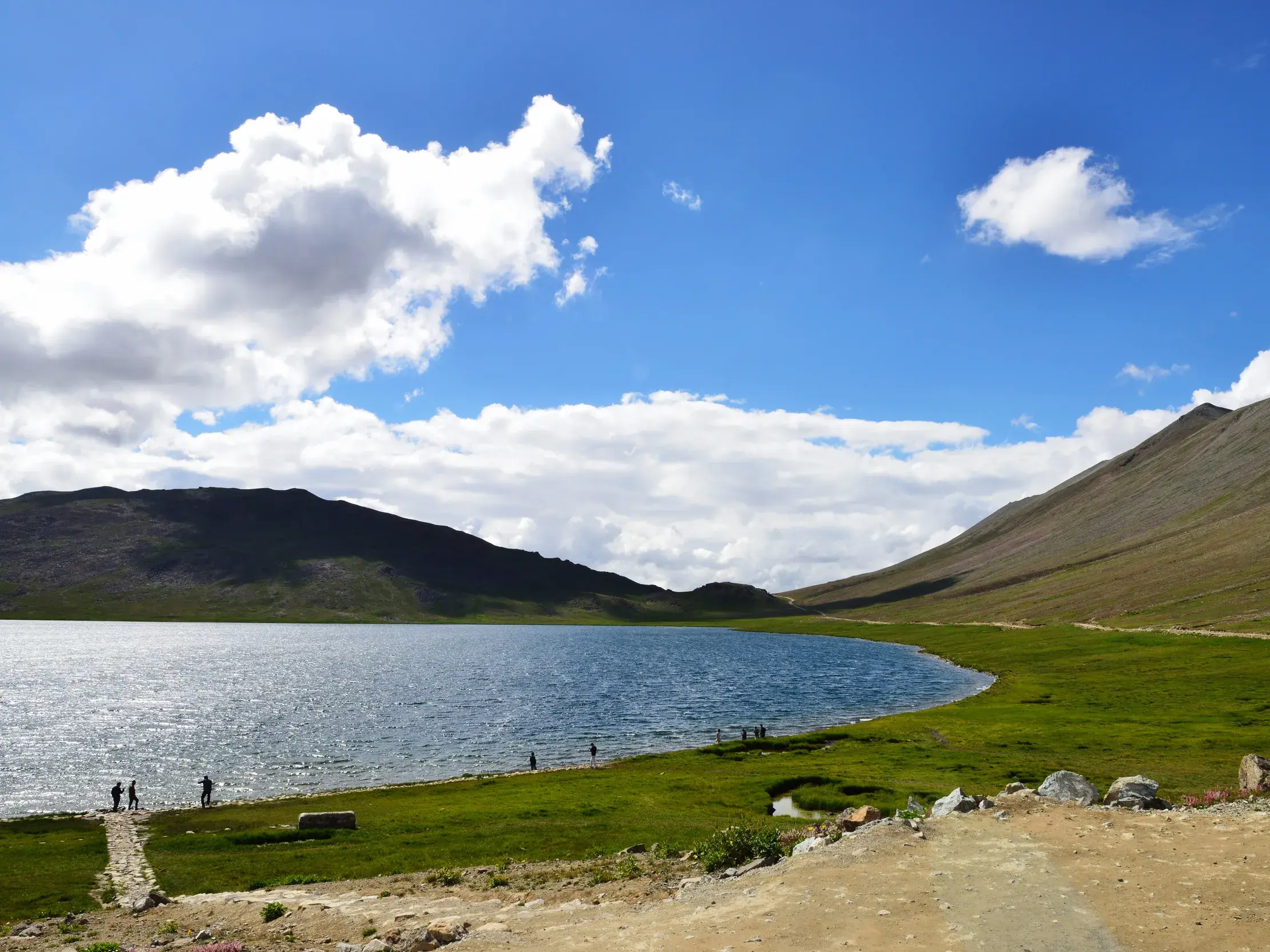 Wanderer am Ufer des blauen Sheosar-Sees in der weiten Hochebene des Deosai-Nationalparks in Pakistan.
