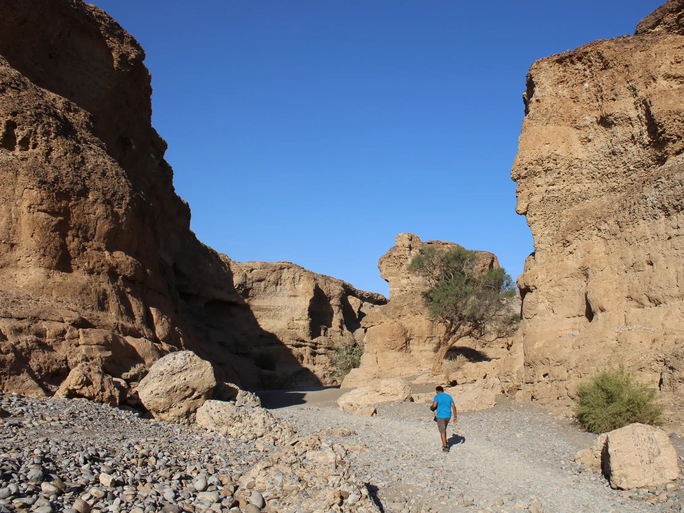 Ein Hauser-Reisegast wandert auf einem steinigen Pfad durch den engen, von hohen Felswänden gesäumten Sesriem Canyon in Namibia.