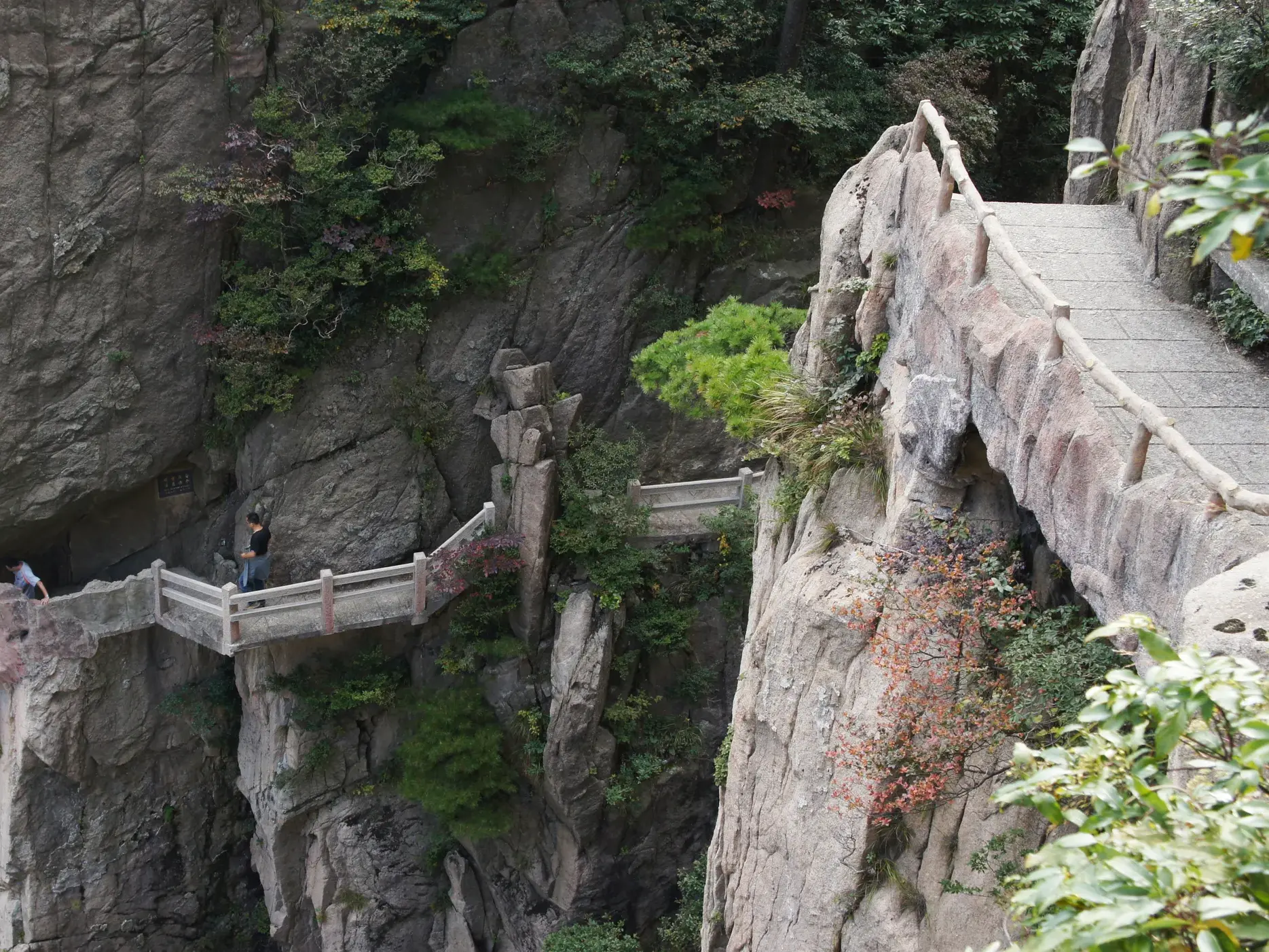 Wanderer auf einem spektakulären, in die Felswand gehauenen Weg im Huang Shan Gebirge, einer Station der Trekkingreise in China.