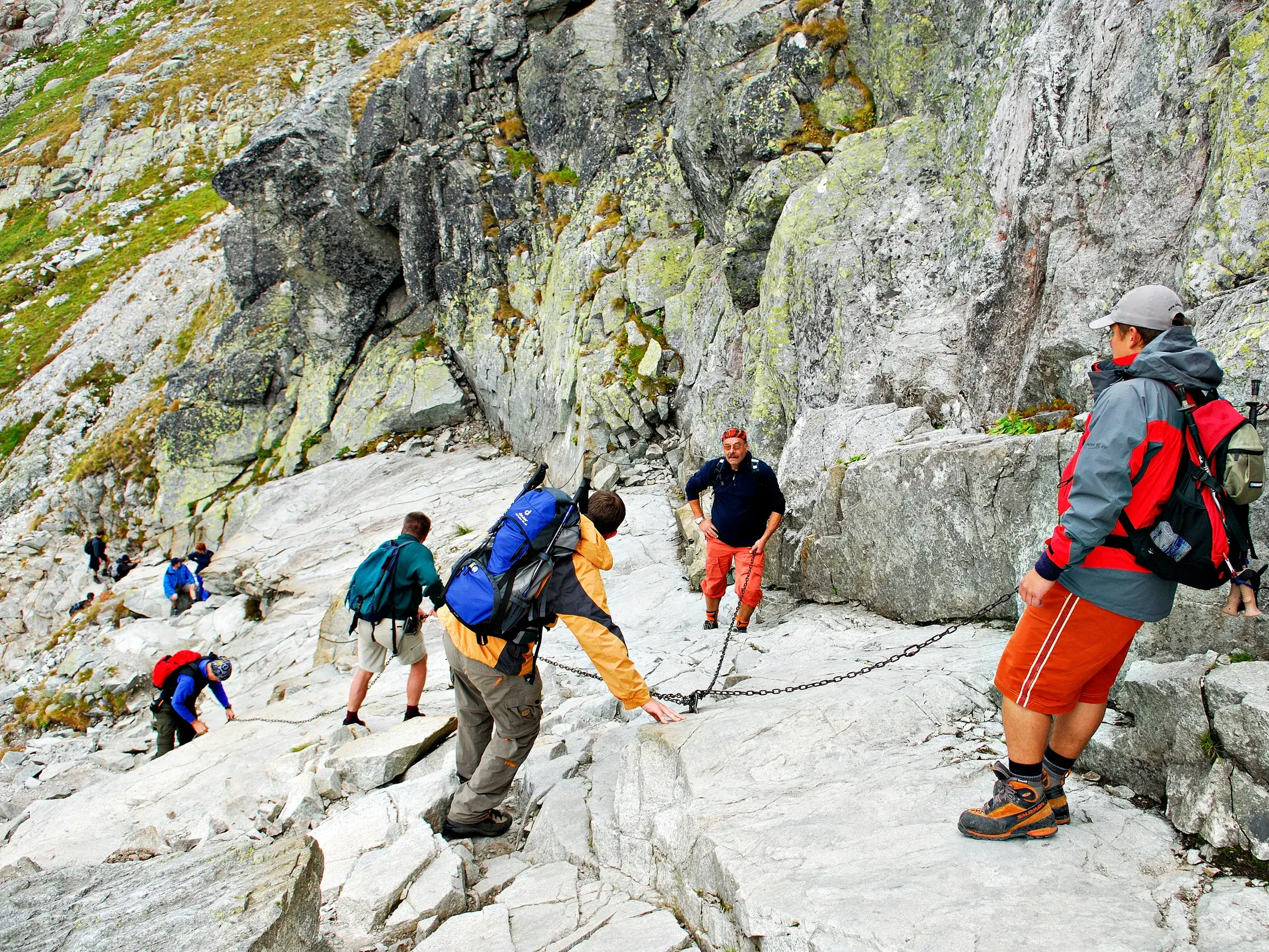 Eine Wandergruppe steigt über einen kettenversicherten, felsigen Steig beim Trekking in der Hohen Tatra in der Slowakei auf.