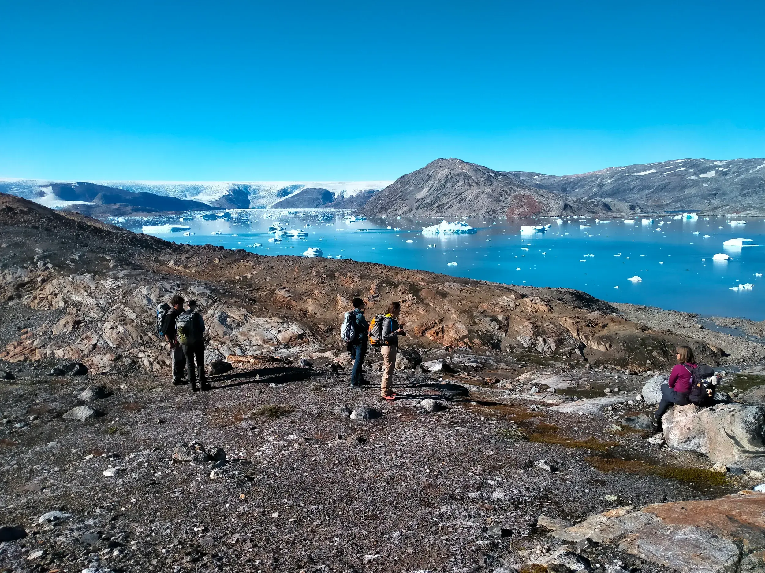 Kleine Wandergruppe bei einer Trekking-Pause in Ostgrönland mit Blick auf den eisigen Johan-Petersen-Fjord und das Inlandeis.