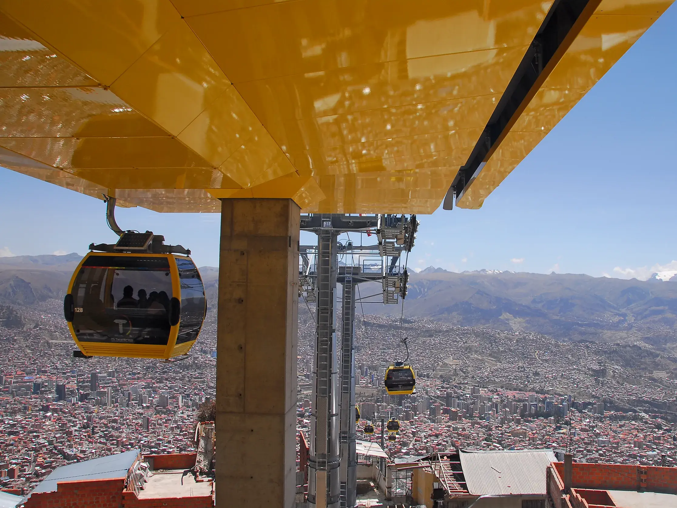 Gelbe Seilbahngondeln schweben über dem riesigen Talkessel von La Paz, mit Panoramablick auf die Anden in Bolivien.