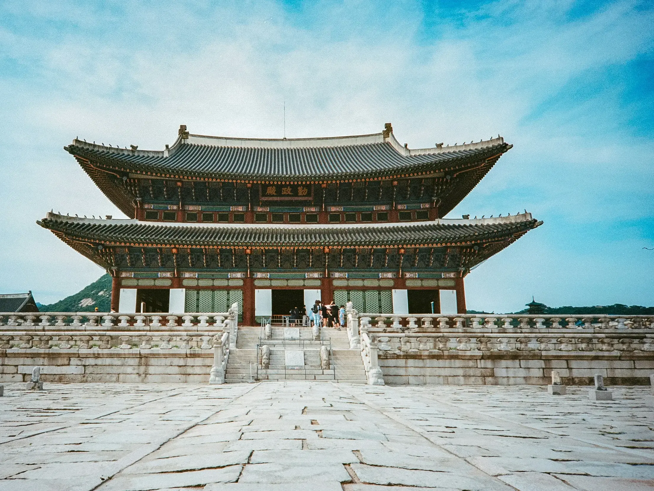 Der historische Gyeongbokgung-Palast in Seoul mit seinem geschwungenen Ziegeldach über einem weiten, steinernen Vorplatz.