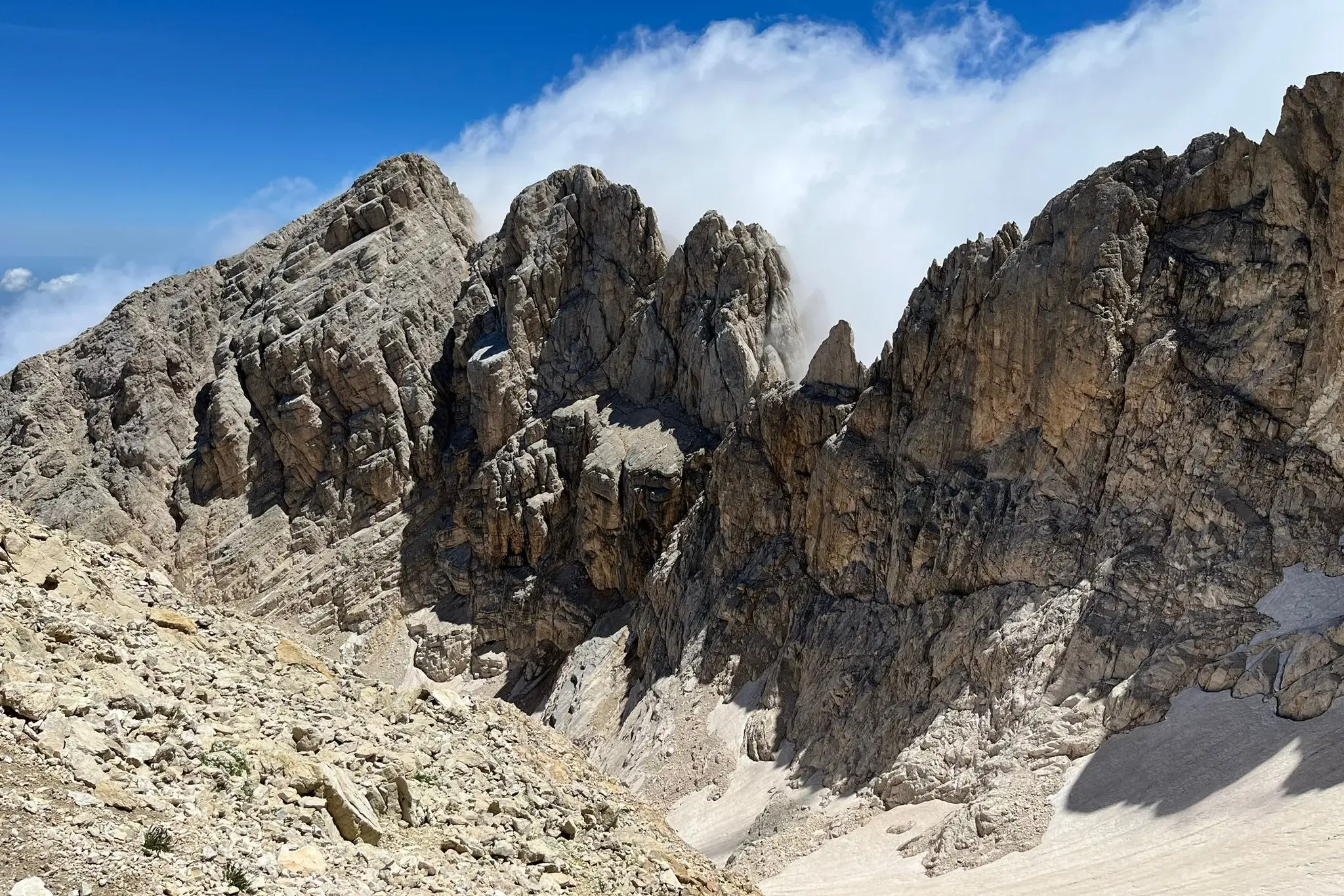 Auf einer Wanderung im Gran Sasso Nationalpark blickt man auf steile Felsgipfel und letzte Schneefelder im Tal.