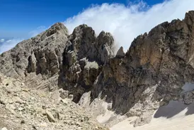 Auf einer Wanderung im Gran Sasso Nationalpark blickt man auf steile Felsgipfel und letzte Schneefelder im Tal.