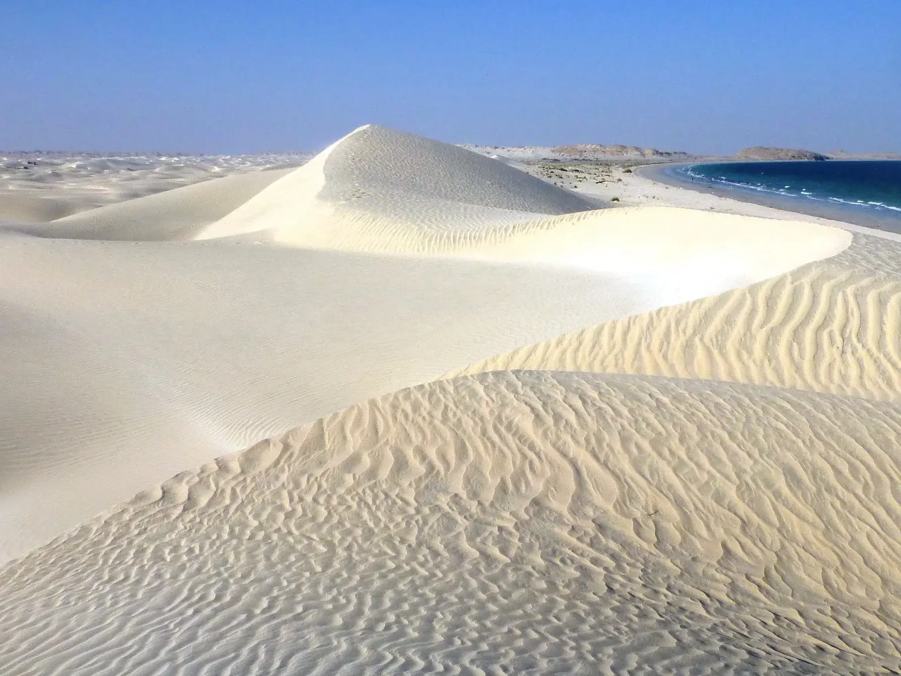 Wanderung durch die weißen Sugar Dunes von Al-Khaluf im Oman mit Blick auf das endlose Dünenmeer und den Indischen Ozean.