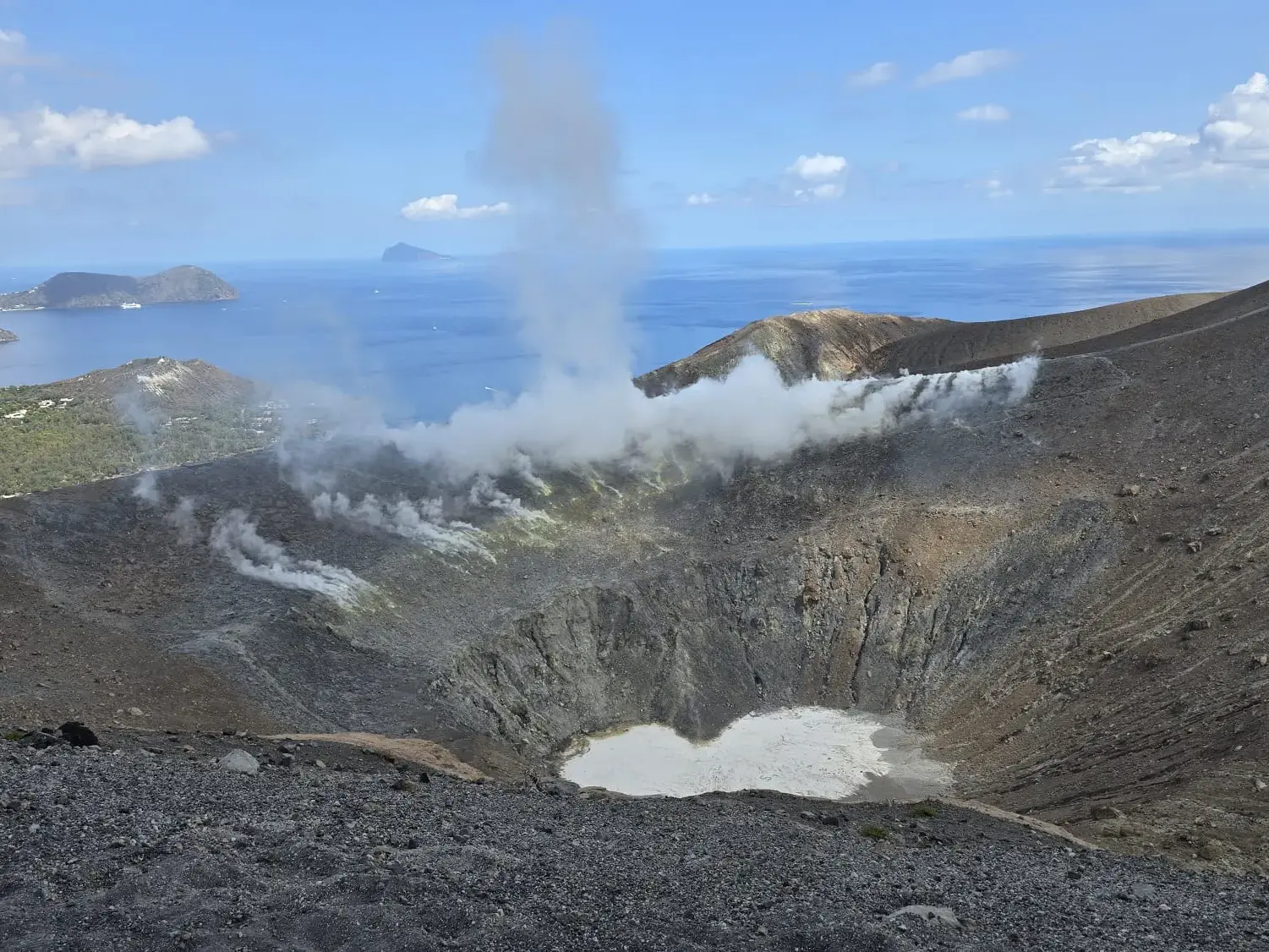 Panoramablick vom rauchenden Gran Cratere auf Vulcano über das tiefblaue Meer und die benachbarten Äolischen Inseln.