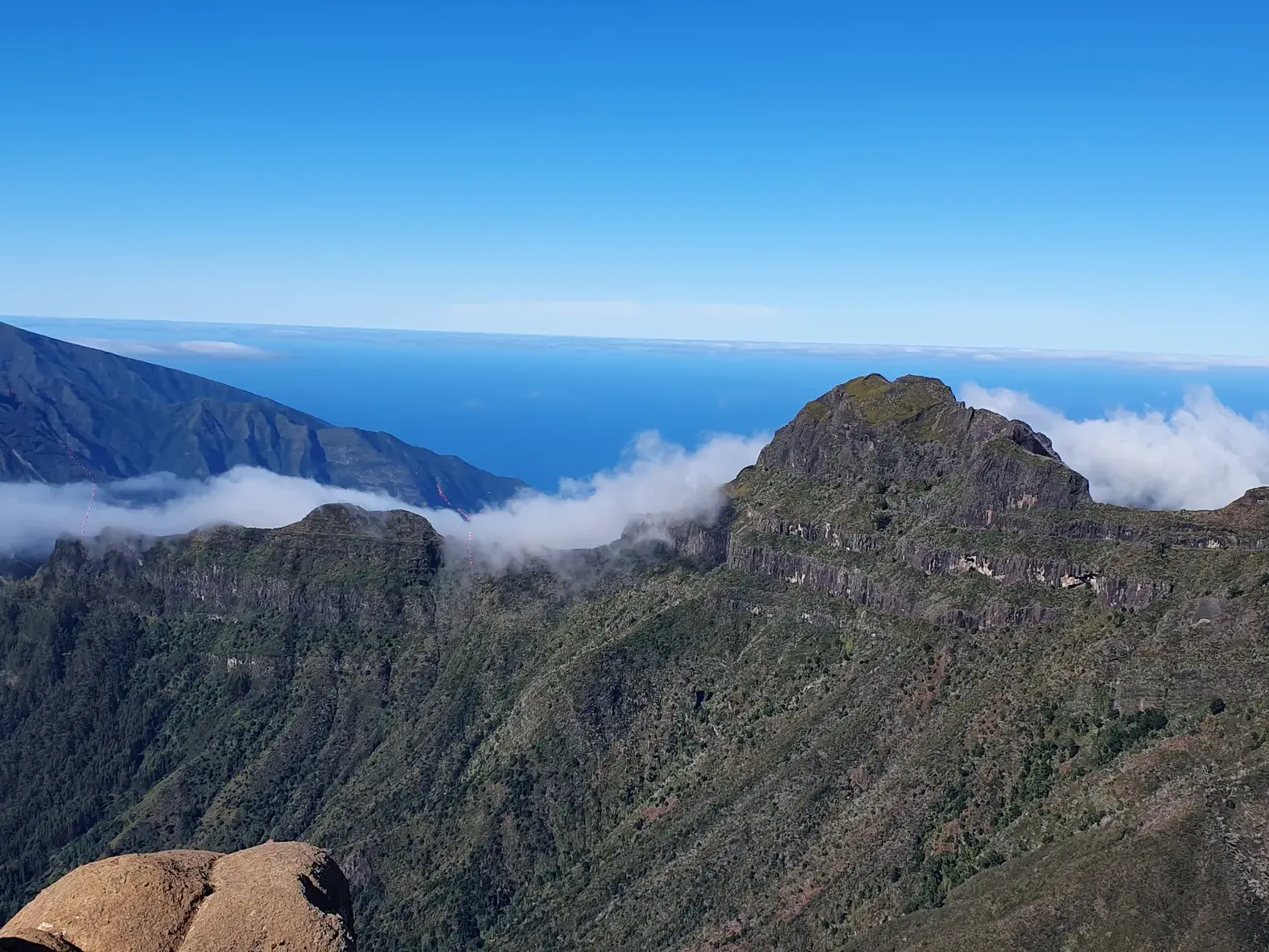 Majestätischer Ausblick beim Trekking im Zentralmassiv Madeiras über felsige Gipfel und Wolken auf den Atlantik.