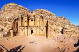Eine kleine Wandergruppe steht vor dem monumentalen Felsenkloster Ed-Deir in Petra, einem Highlight der Jordanien-Reise.