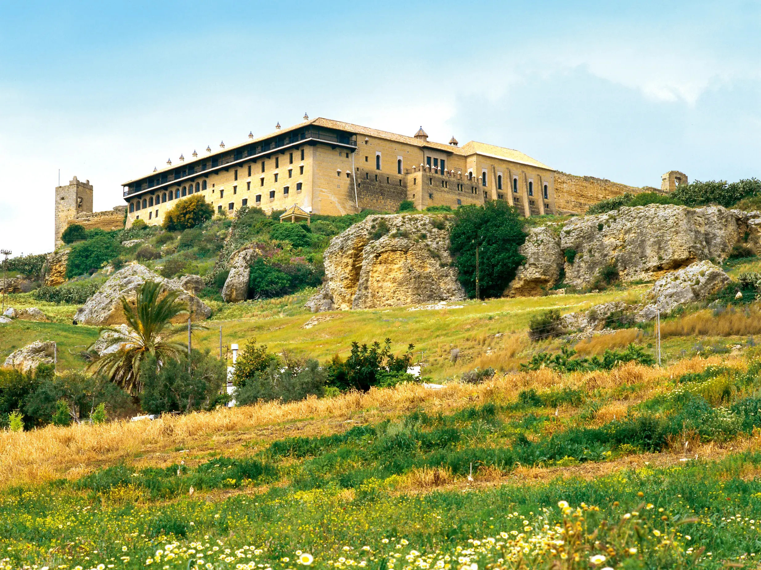 Der Parador de Carmona, eine ehemalige maurische Festung, thront auf einem grünen Hügel in der Landschaft Andalusiens.