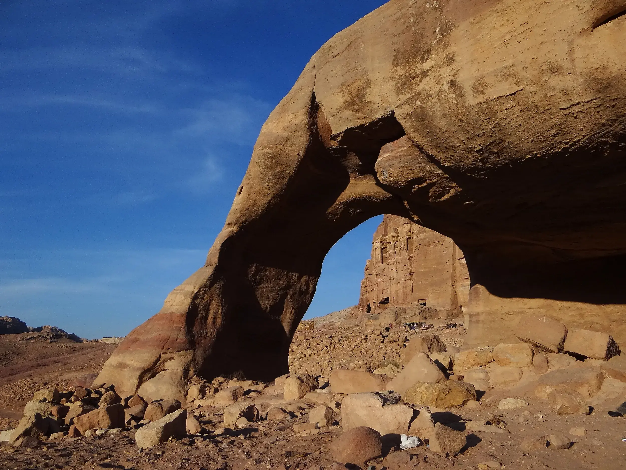 Ein natürlicher Sandsteinbogen rahmt den Blick auf die antiken Königsgräber der Felsenstadt Petra in Jordanien ein.