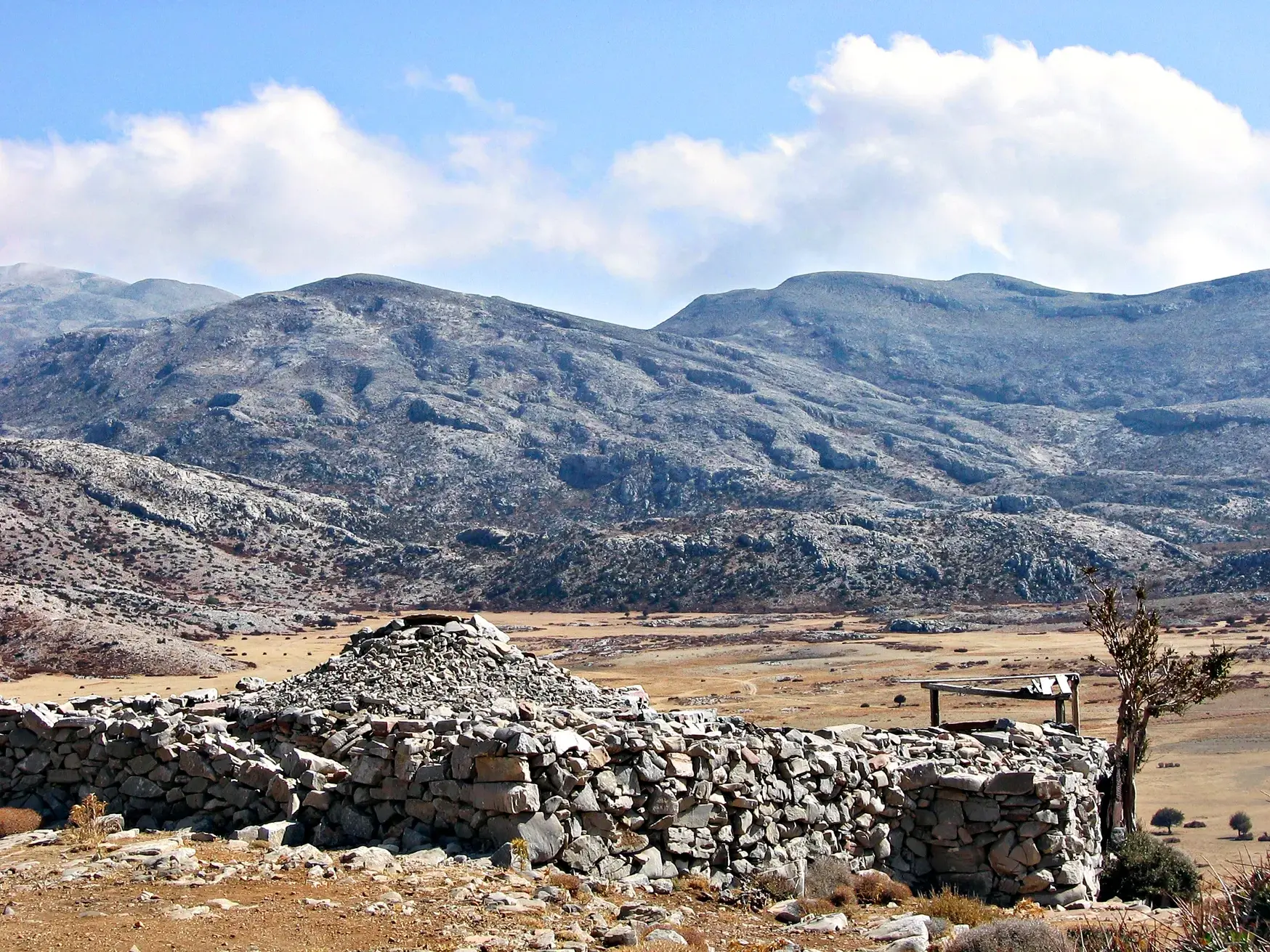 Alte Hirtenhütte aus Stein auf der kargen Omalos-Hochebene, im Hintergrund die schroffen Gipfel der Lefka Ori auf Kreta.