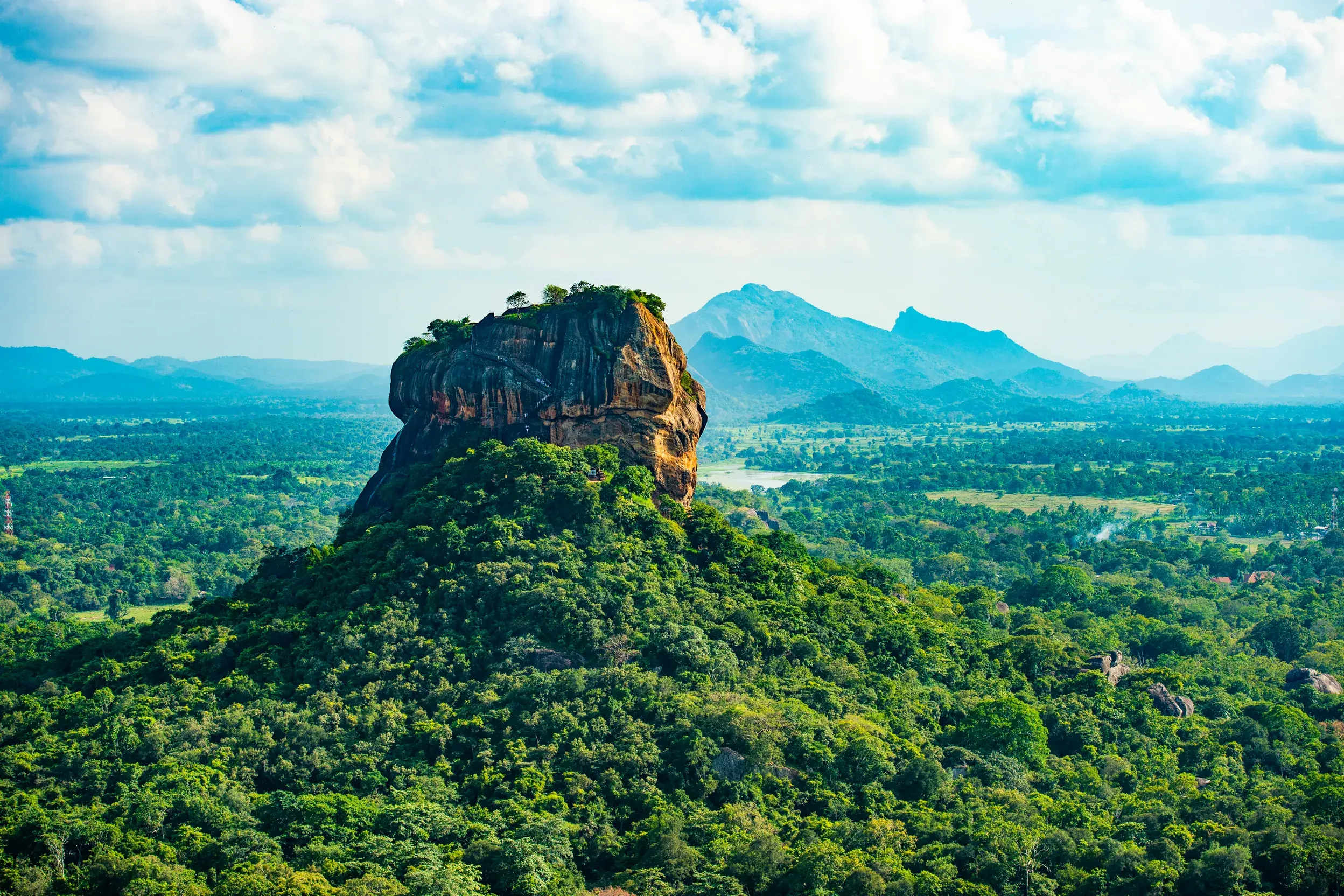 Panoramablick auf den berühmten Löwenfelsen Sigiriya, der majestätisch aus dem dichten, grünen Dschungel Sri Lankas emporragt.