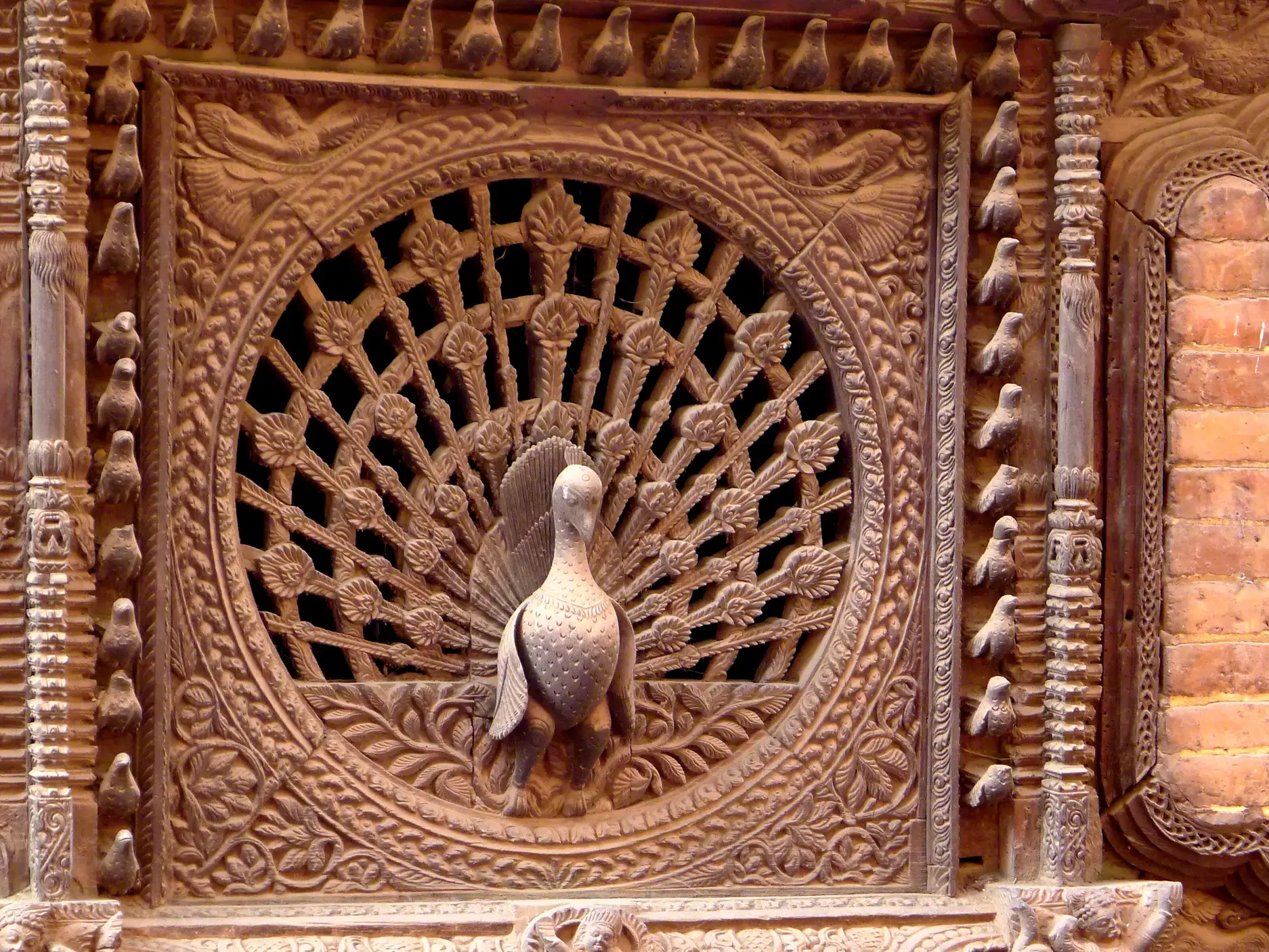 Nahaufnahme des kunstvoll geschnitzten Pfauenfensters in Bhaktapur, ein Highlight der Newari-Handwerkskunst in Nepal.