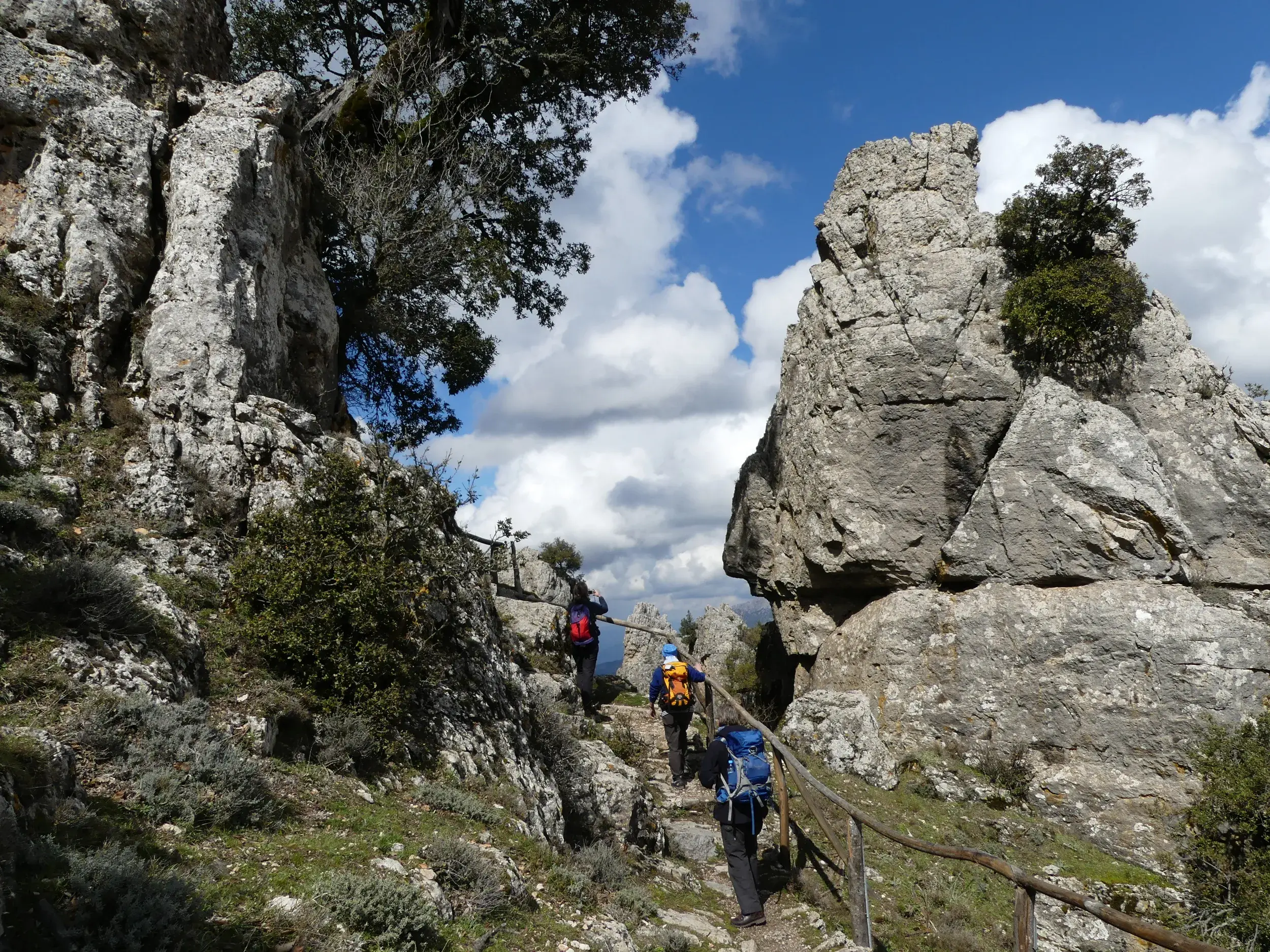 Wandergruppe auf einem schmalen Pfad durch die zerklüftete Felslandschaft des Supramonte-Gebirges auf Sardinien.