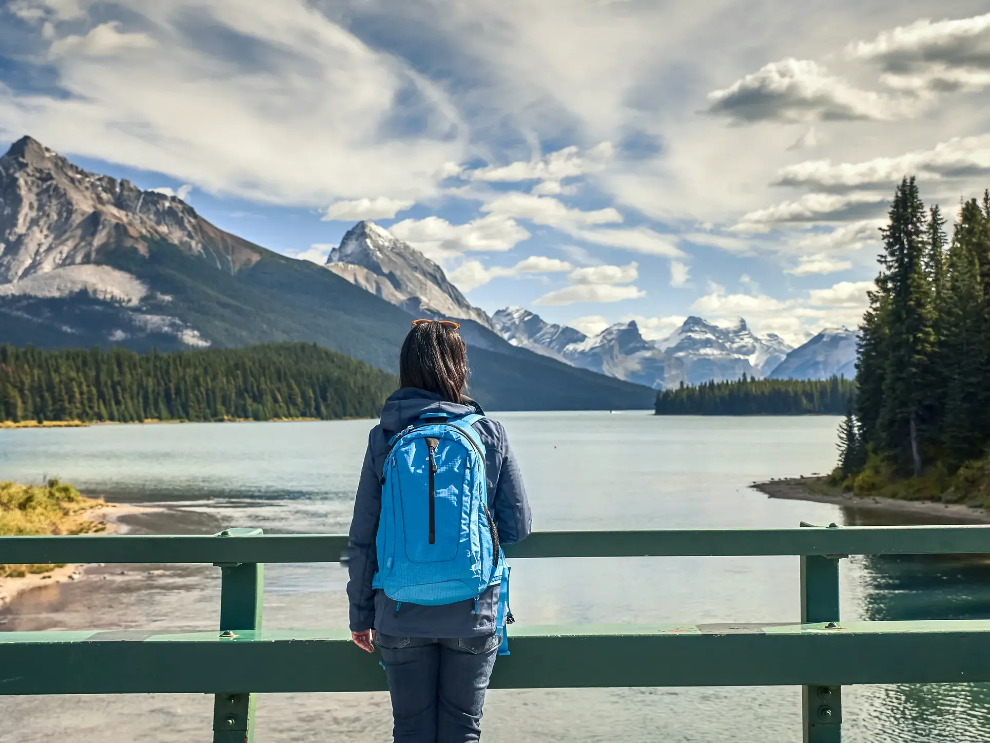 Eine Reisende mit Rucksack genießt den Panoramablick auf den Maligne Lake und die Rocky Mountains im Jasper-Nationalpark.