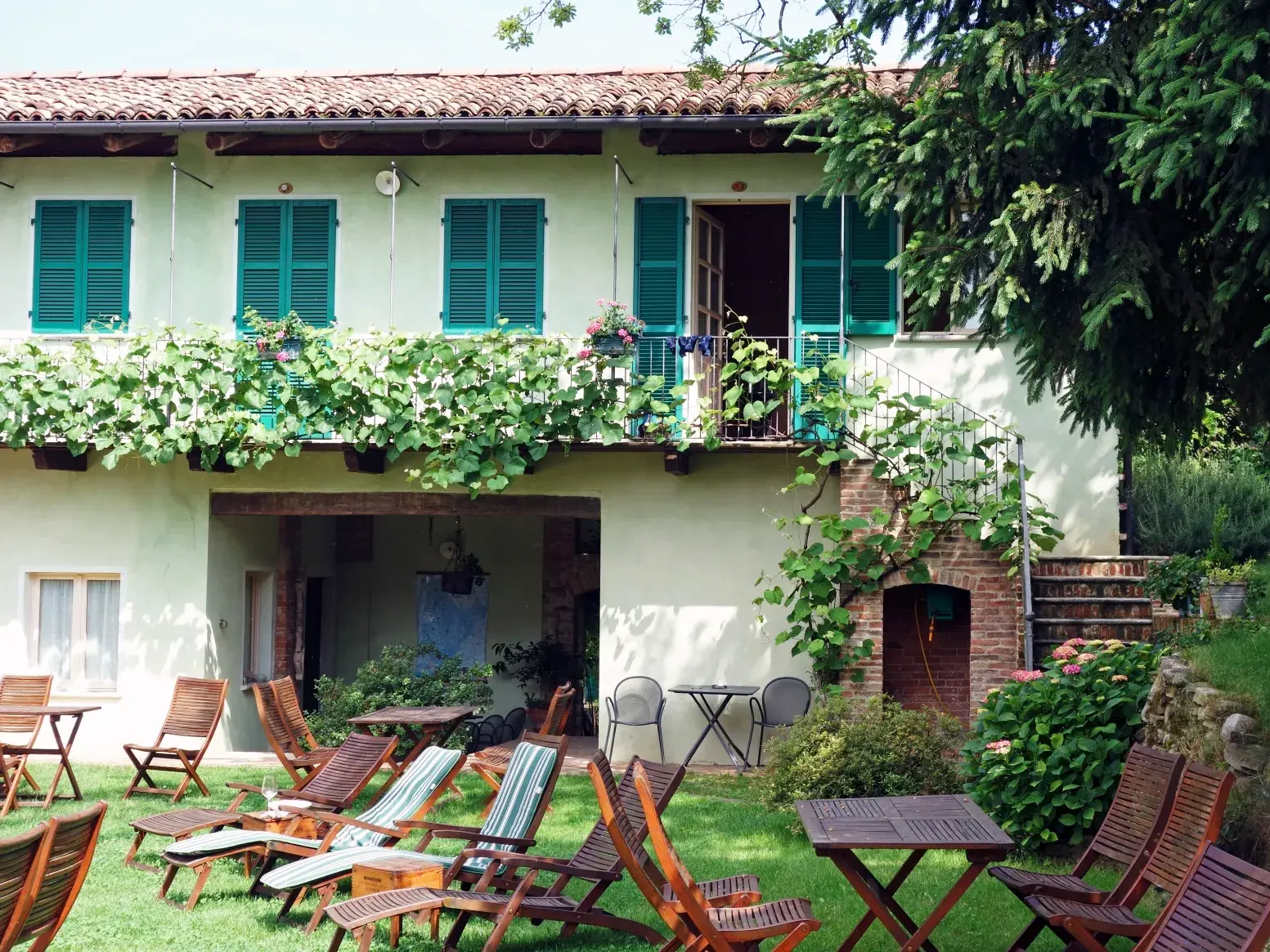 Ein bewachsenes Agriturismo in der Langhe lädt mit Liegestühlen im Garten zur Entspannung nach einer Trekking-Etappe ein.