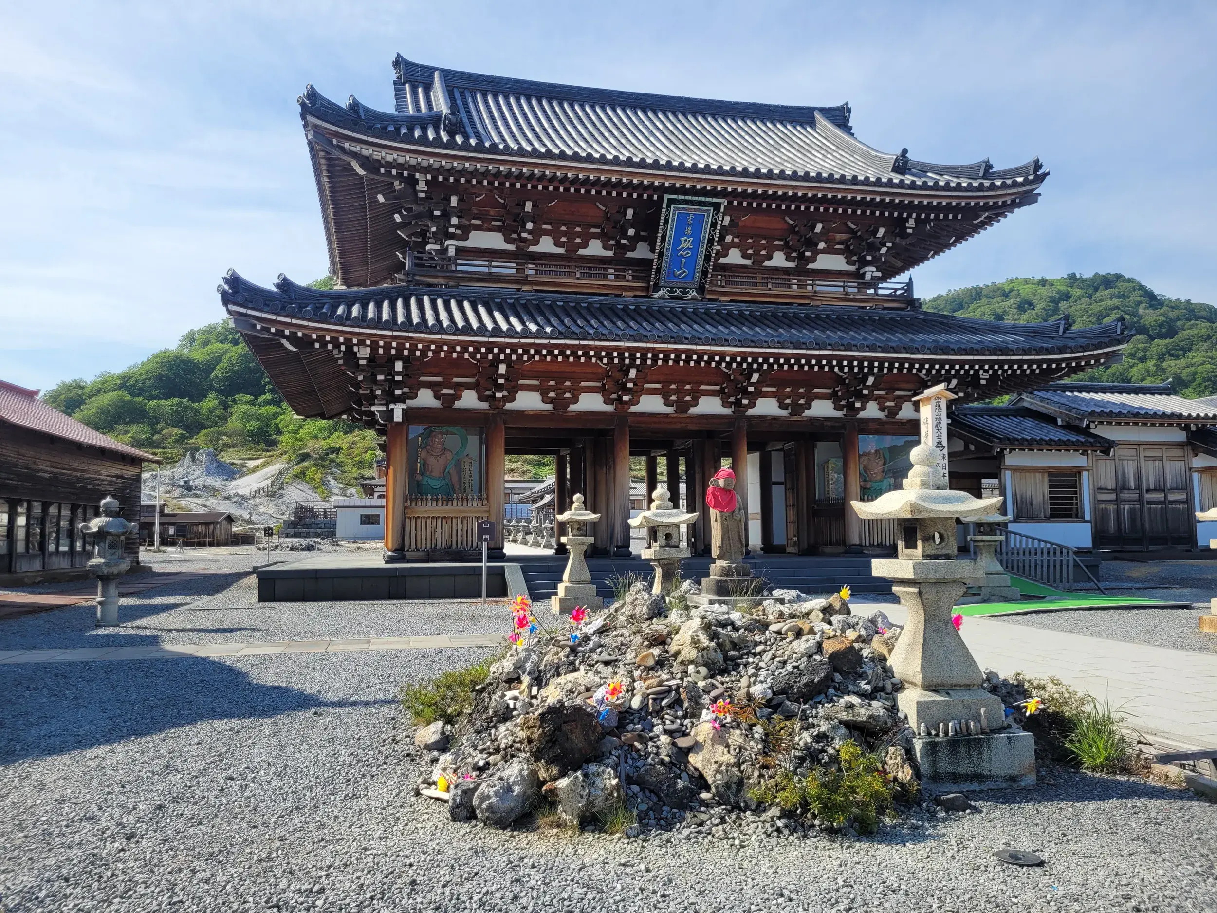 Der majestätische Bodaiji-Tempel am heiligen Berg Osorezan, umgeben von karger Vulkanlandschaft und Steinhaufen mit Windrädern.