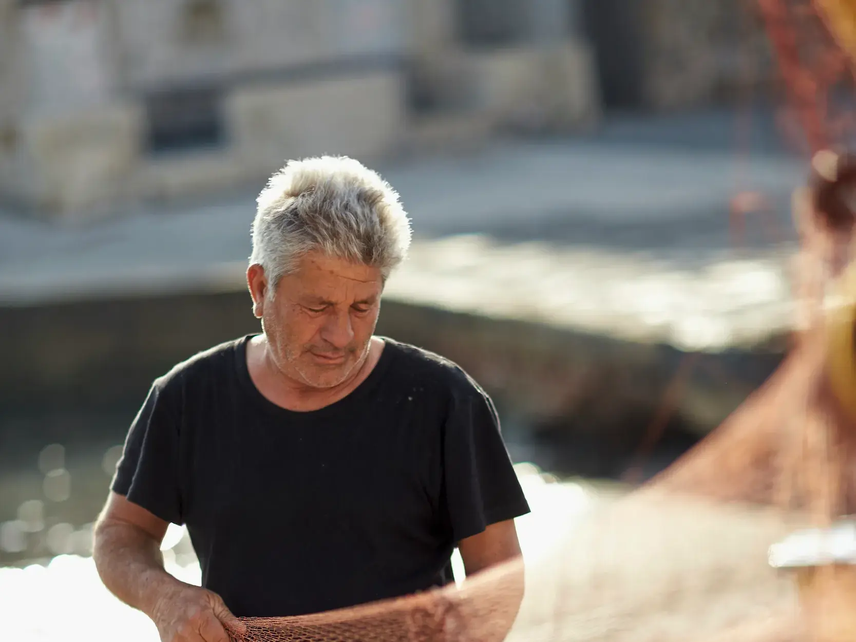 Porträt eines einheimischen Fischers mit grauem Haar, der konzentriert in einem Hafen auf den Äolischen Inseln arbeitet.