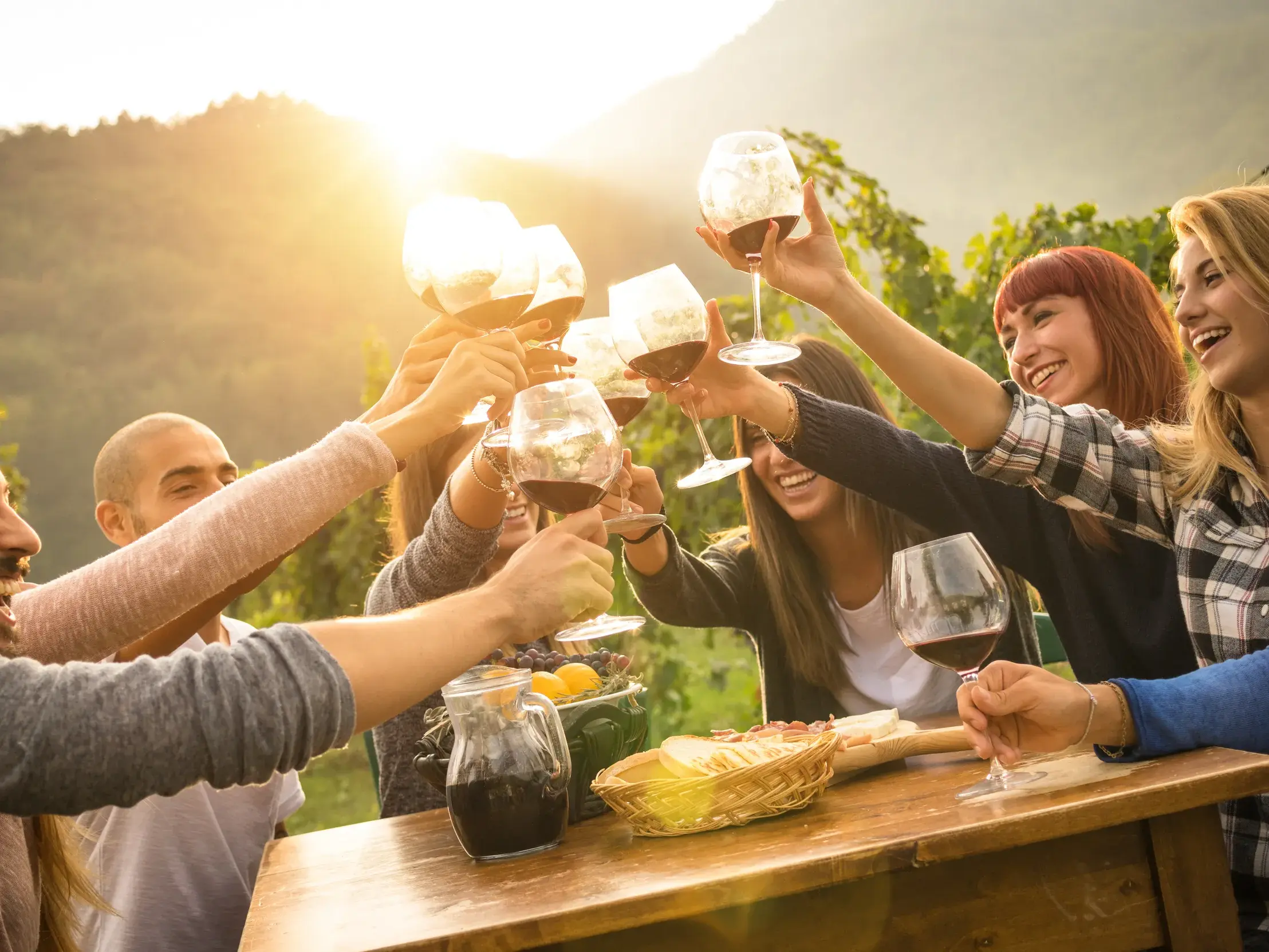 Eine kleine Reisegruppe stößt bei einer Weinprobe auf einem Landgut in der Toskana fröhlich mit Rotwein an.