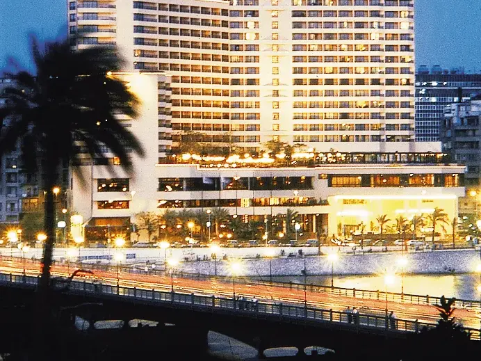 Außenansicht des Hotels Semiramis InterContinental in Kairo bei Nacht, mit Blick auf die belebte Nil-Brücke und die Uferpromenade.