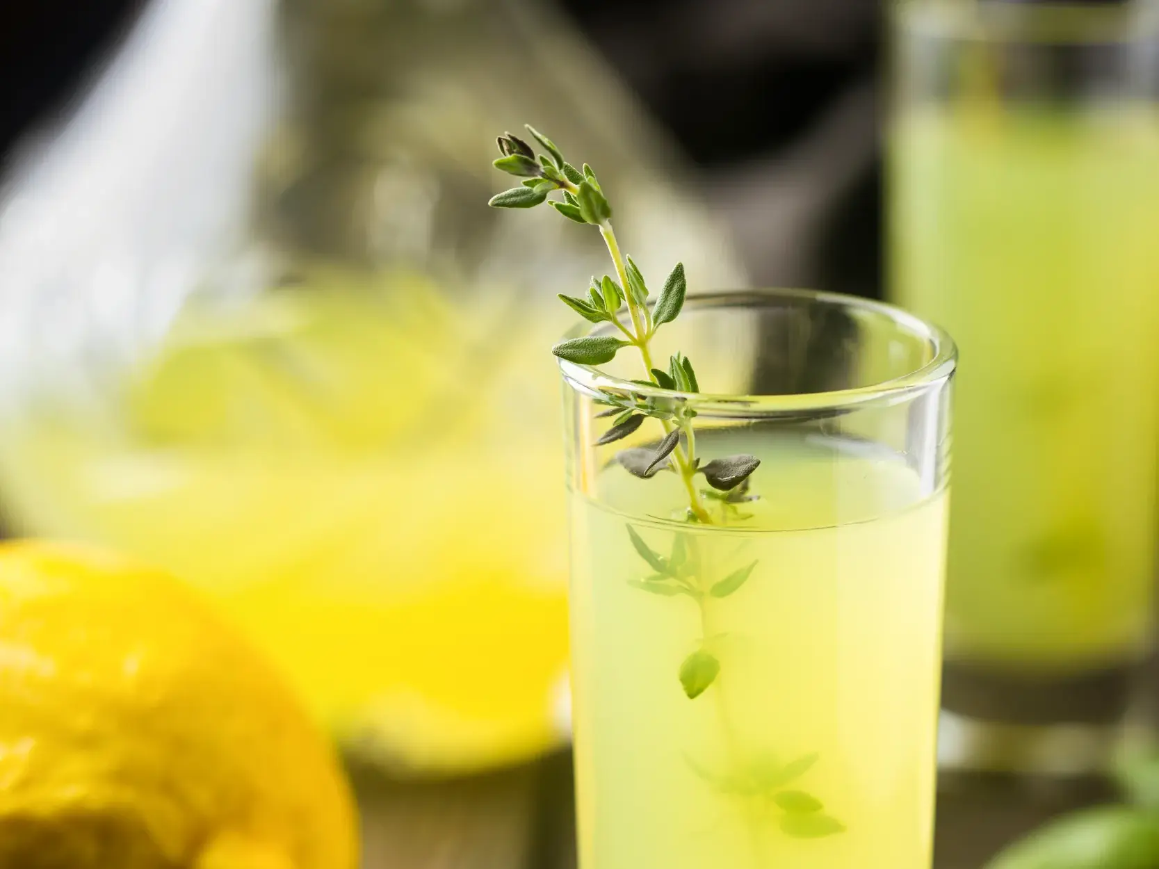 Ein Glas mit einem kühlen, gelben Getränk, garniert mit einem Thymianzweig, ein kulinarischer Genuss auf den Äolischen Inseln.